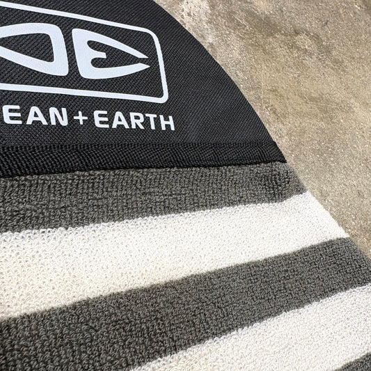 Close-up of a striped rug with 'Ocean + Earth' branding on a textured surface.