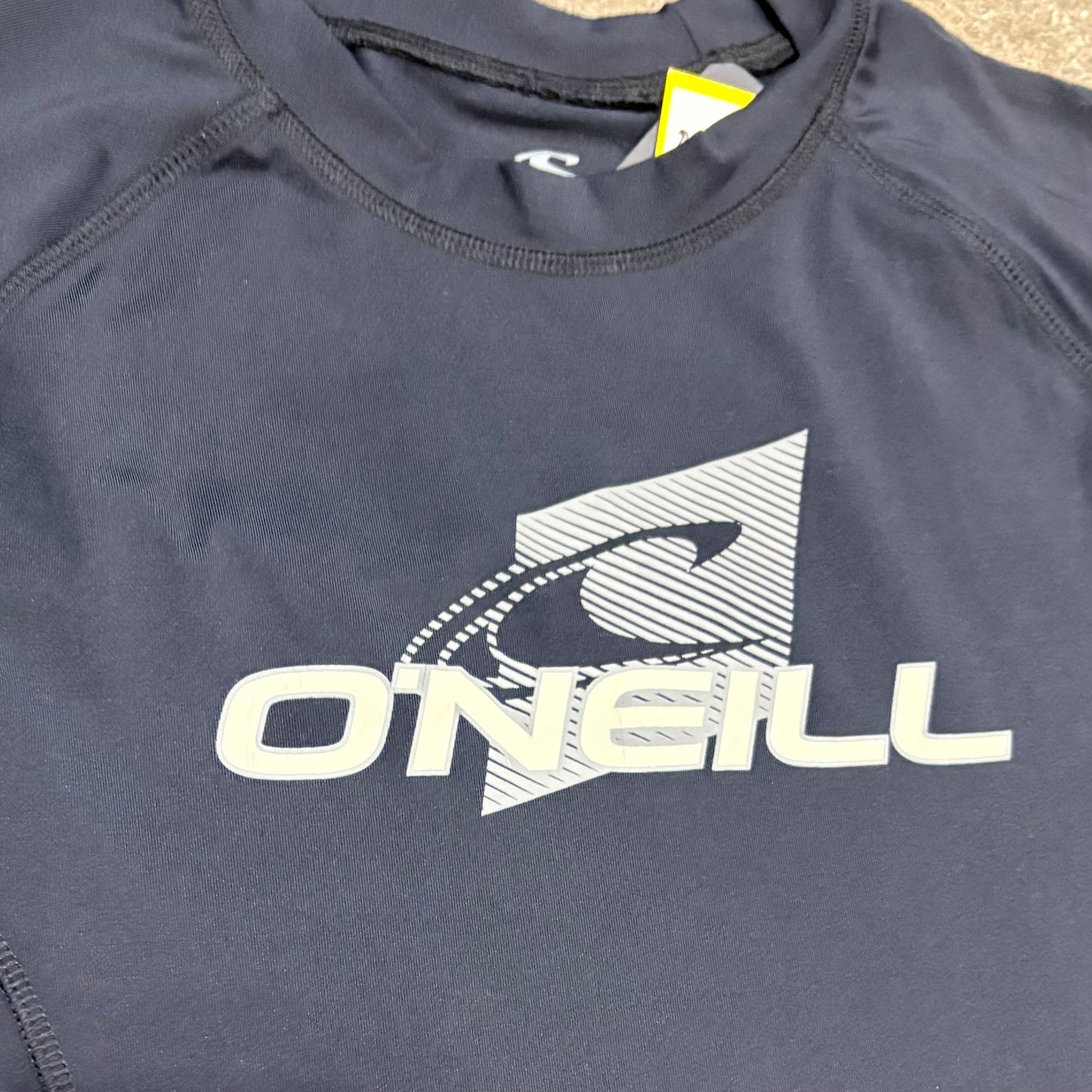 Navy blue shirt with O'Neill logo on a beige surface