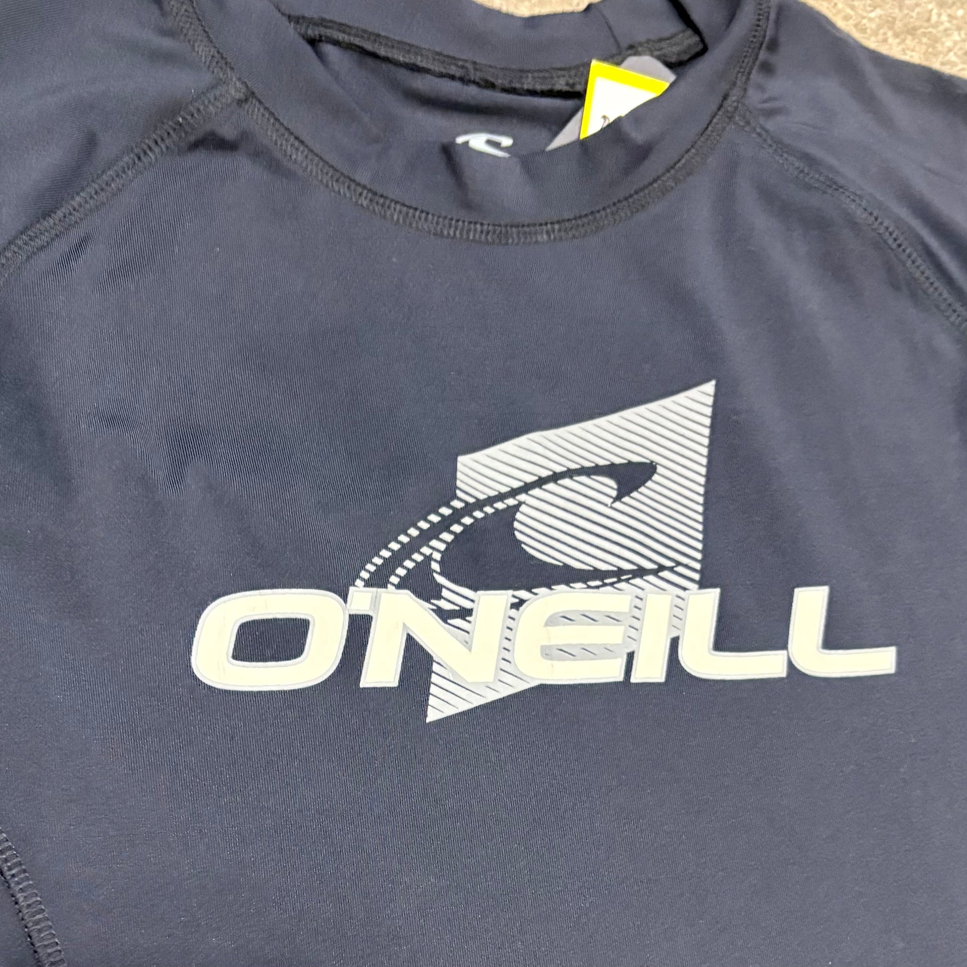 Navy blue shirt with O'Neill logo on a beige surface