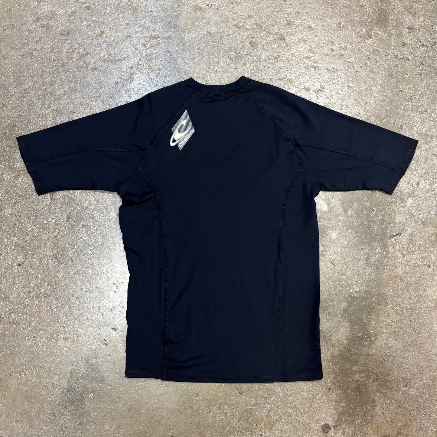 Black t-shirt with a brand logo on a concrete surface