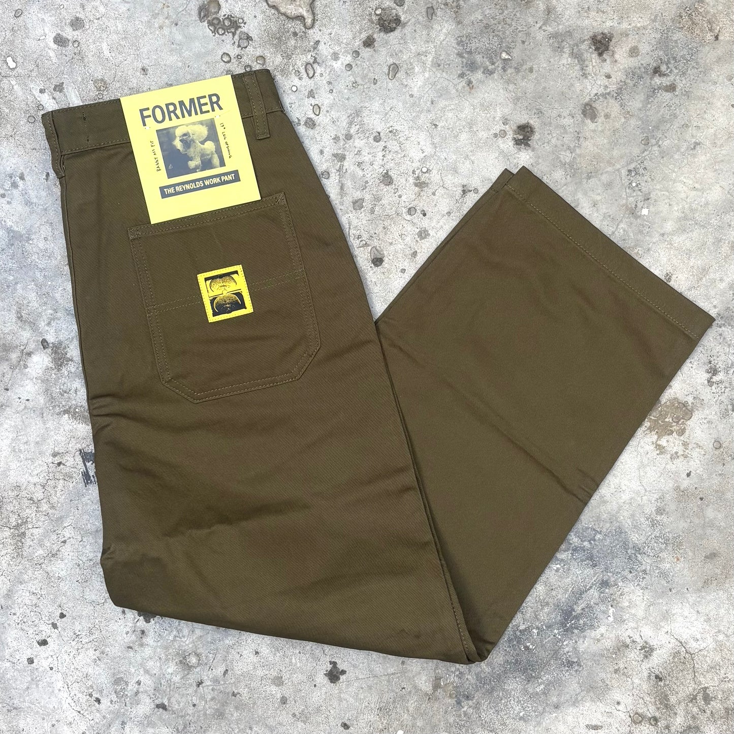 green olive pants with yellow labels on a textured surface
