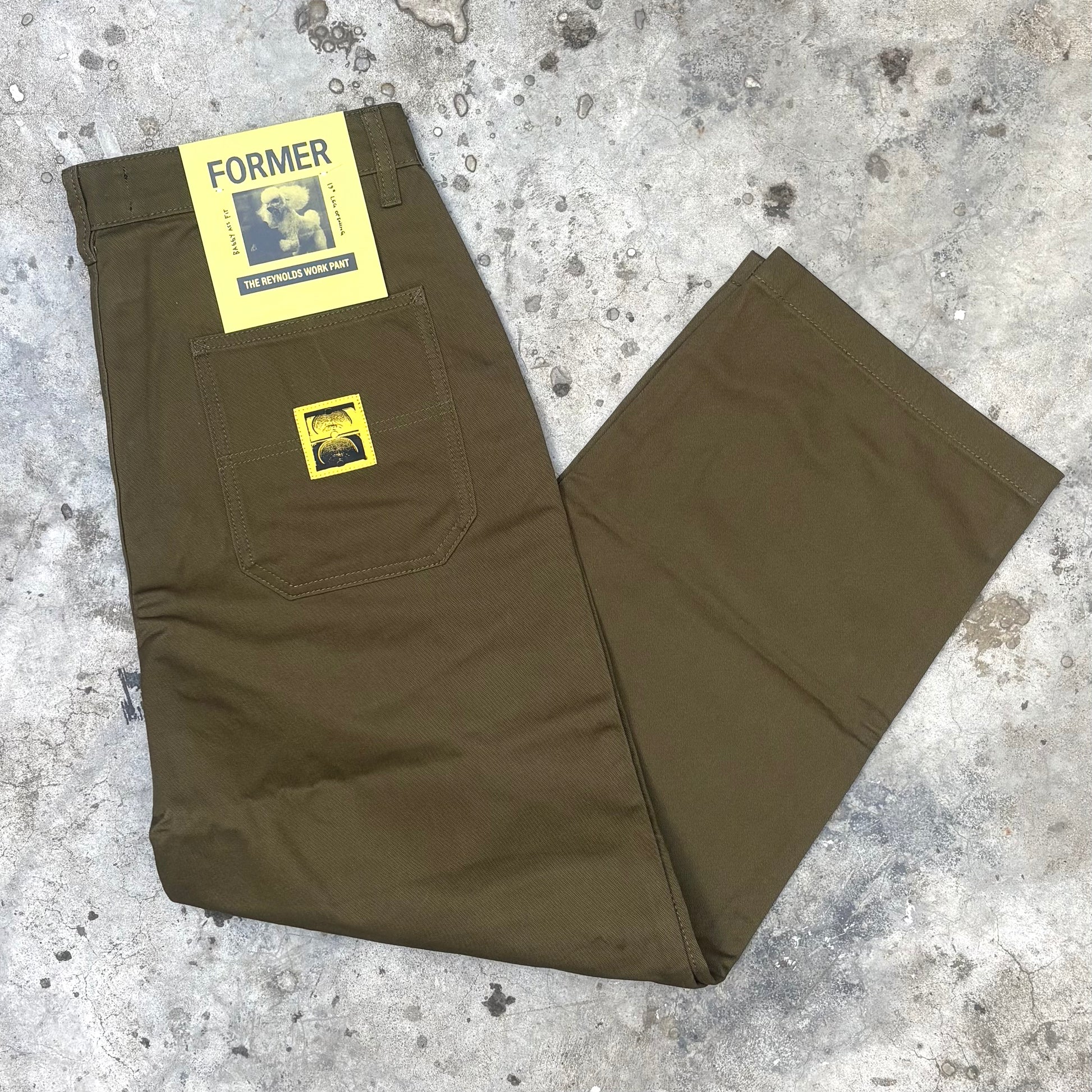 green olive pants with yellow labels on a textured surface
