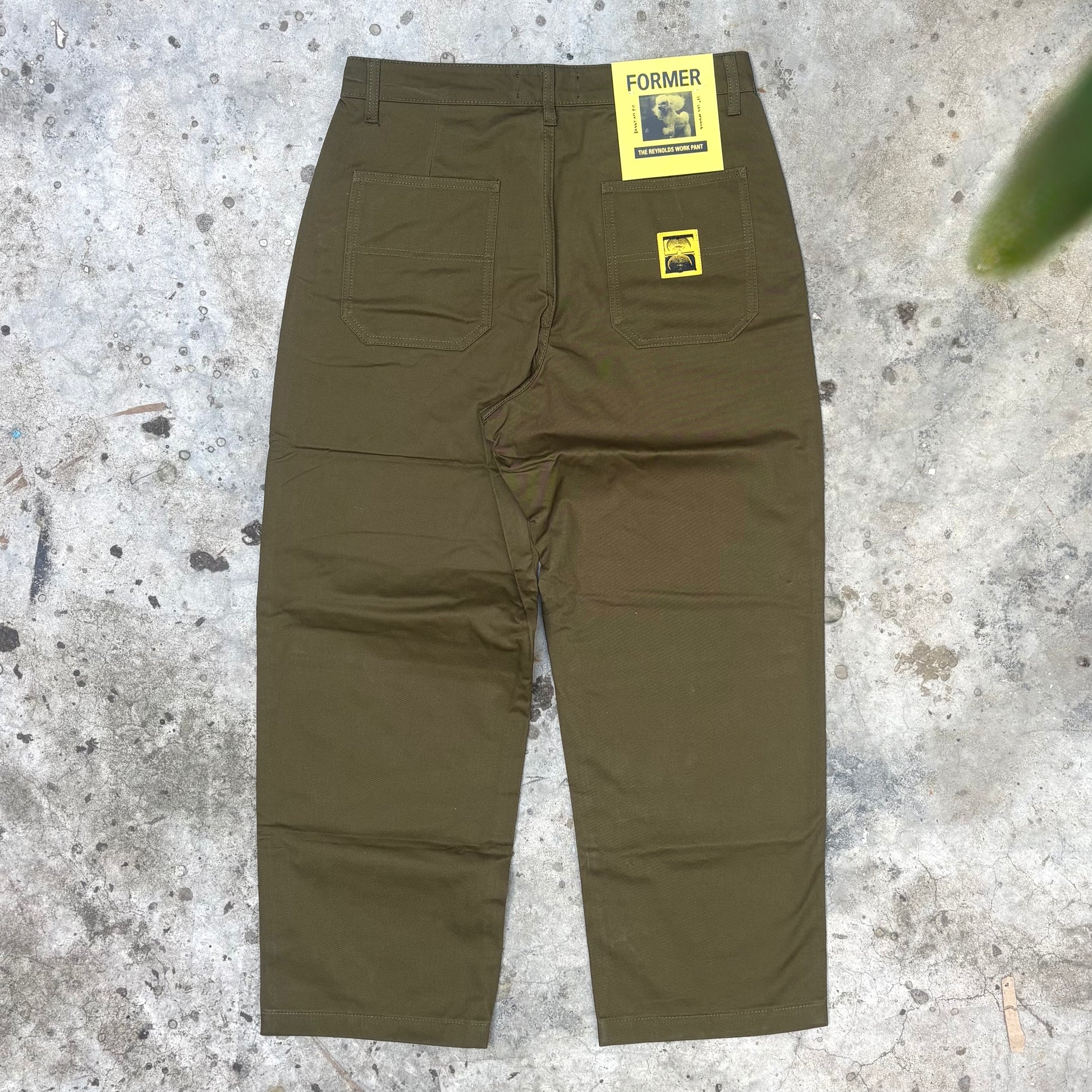 Dark Olive pants with 'Former' labels on a textured surface