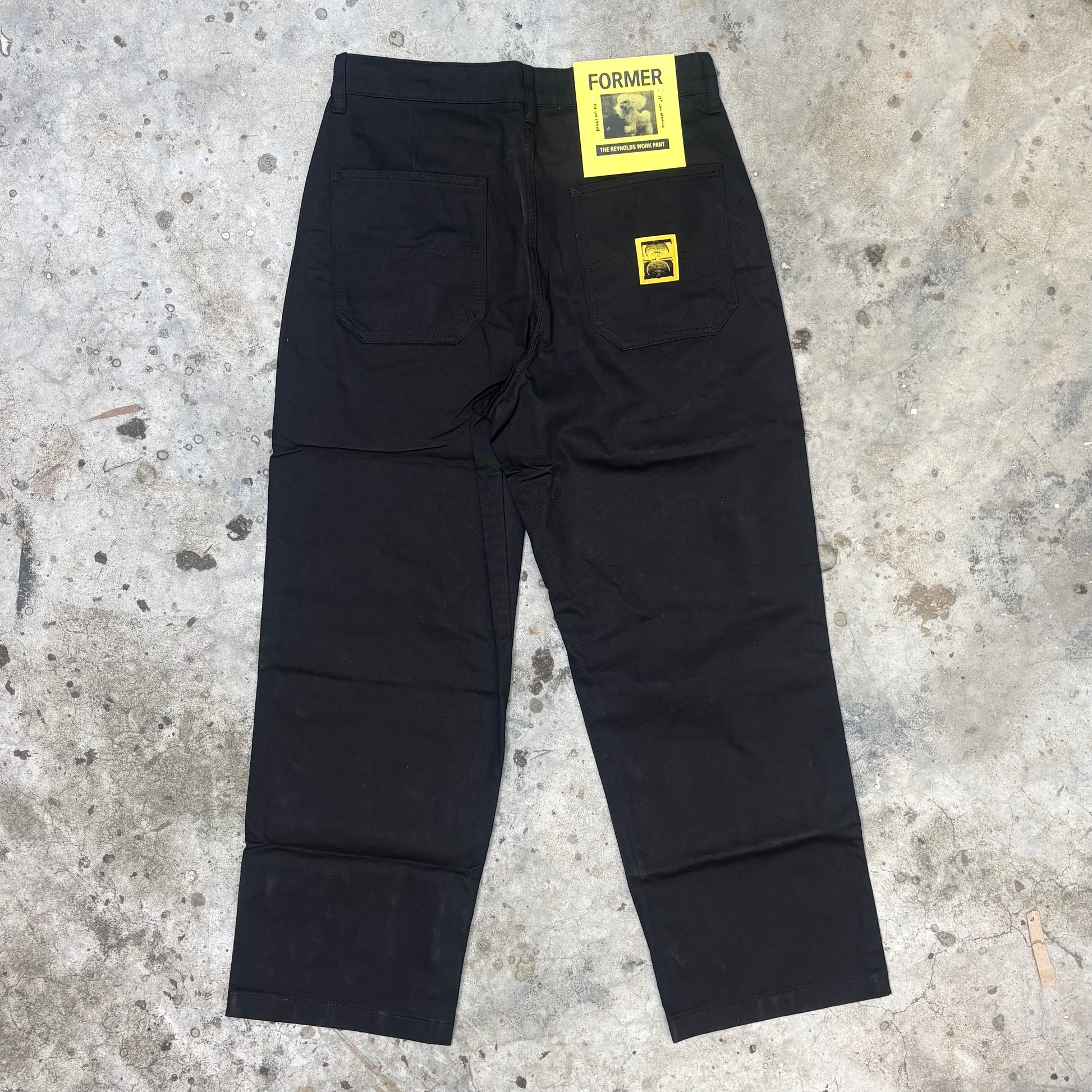 Black pants with yellow tags on a concrete surface