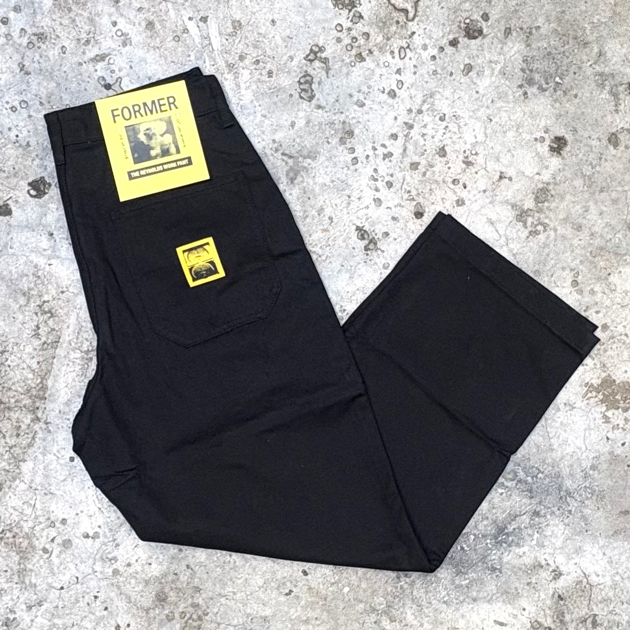 Black pants with yellow labels on a textured gray surface