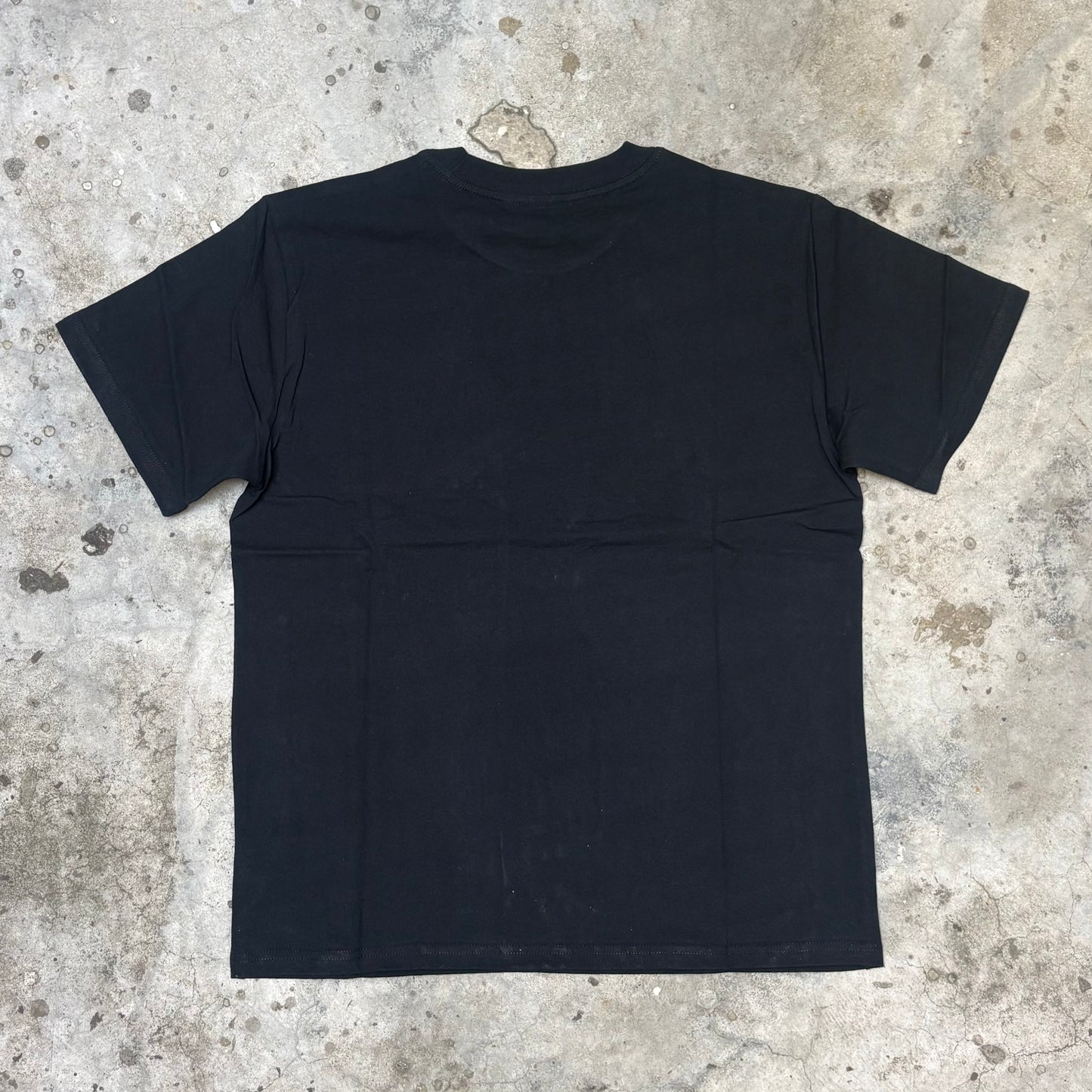 Black t-shirt on a textured concrete floor