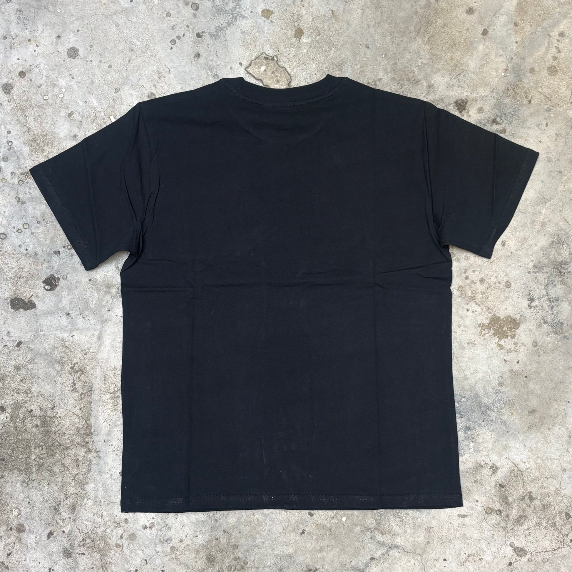 Black t-shirt on a textured concrete floor