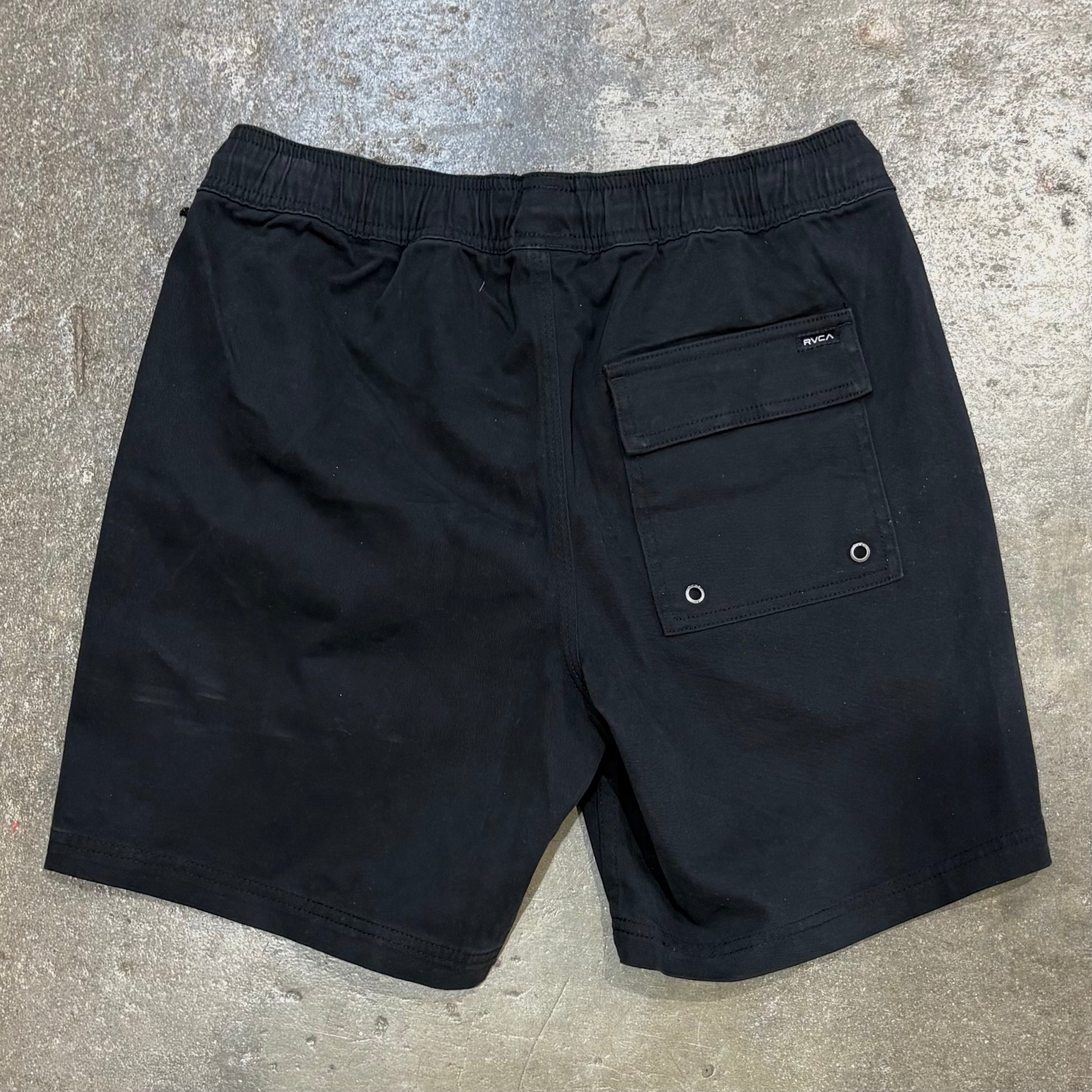 Black shorts with a pocket on a concrete surface