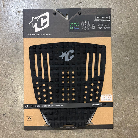 Black surfboard traction pad on a cardboard backing with branding on a concrete surface