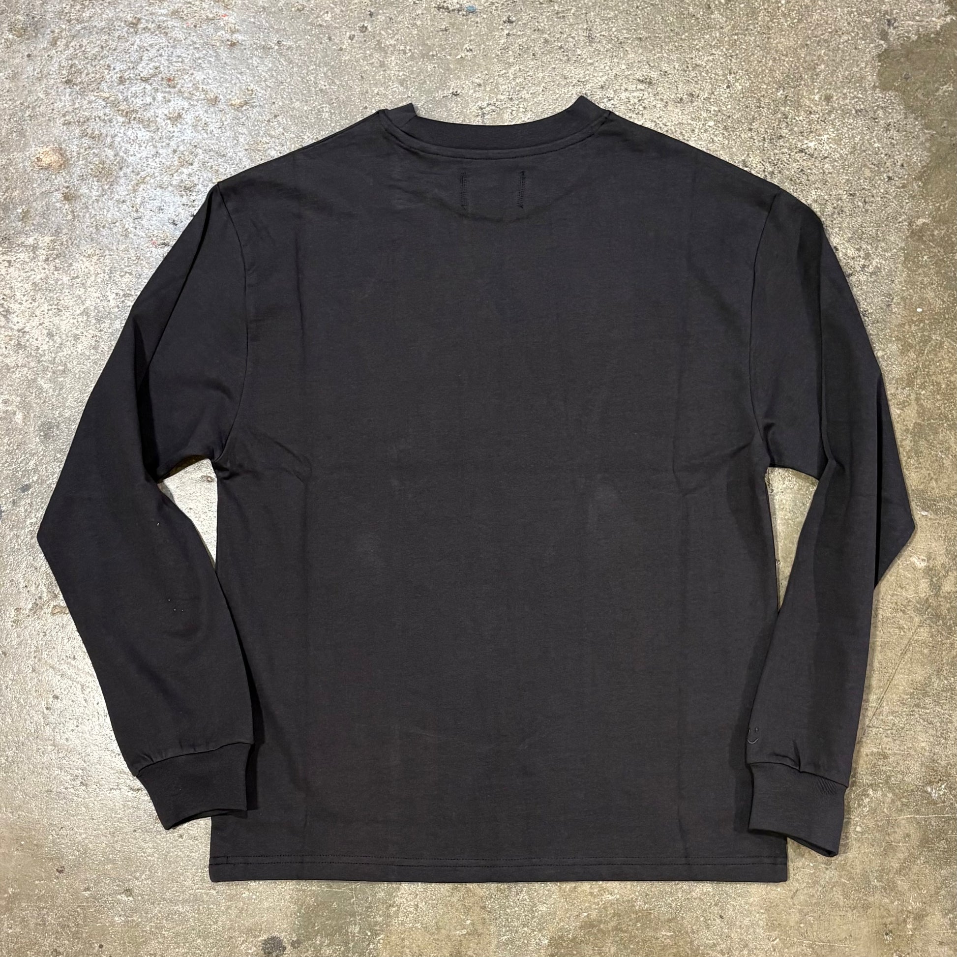 Black long-sleeve shirt on a concrete surface