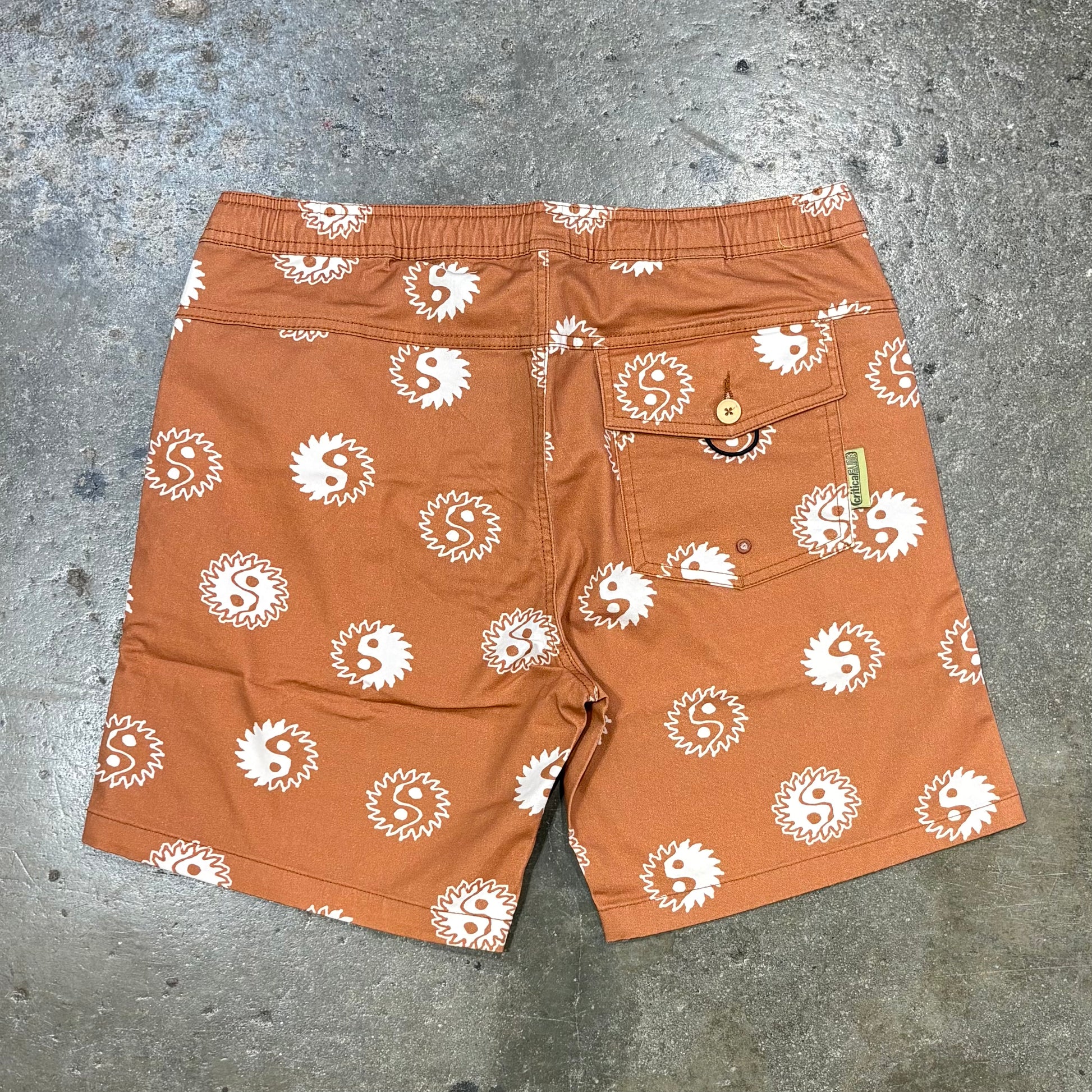 Brown shorts with white pattern on a gray concrete surface