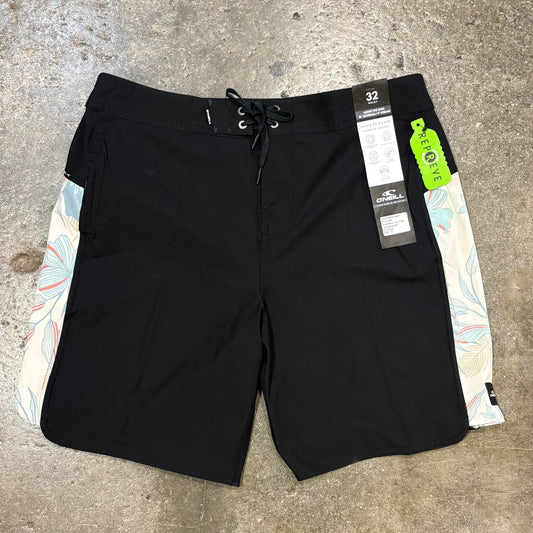 Black board shorts with floral side panels on a concrete surface