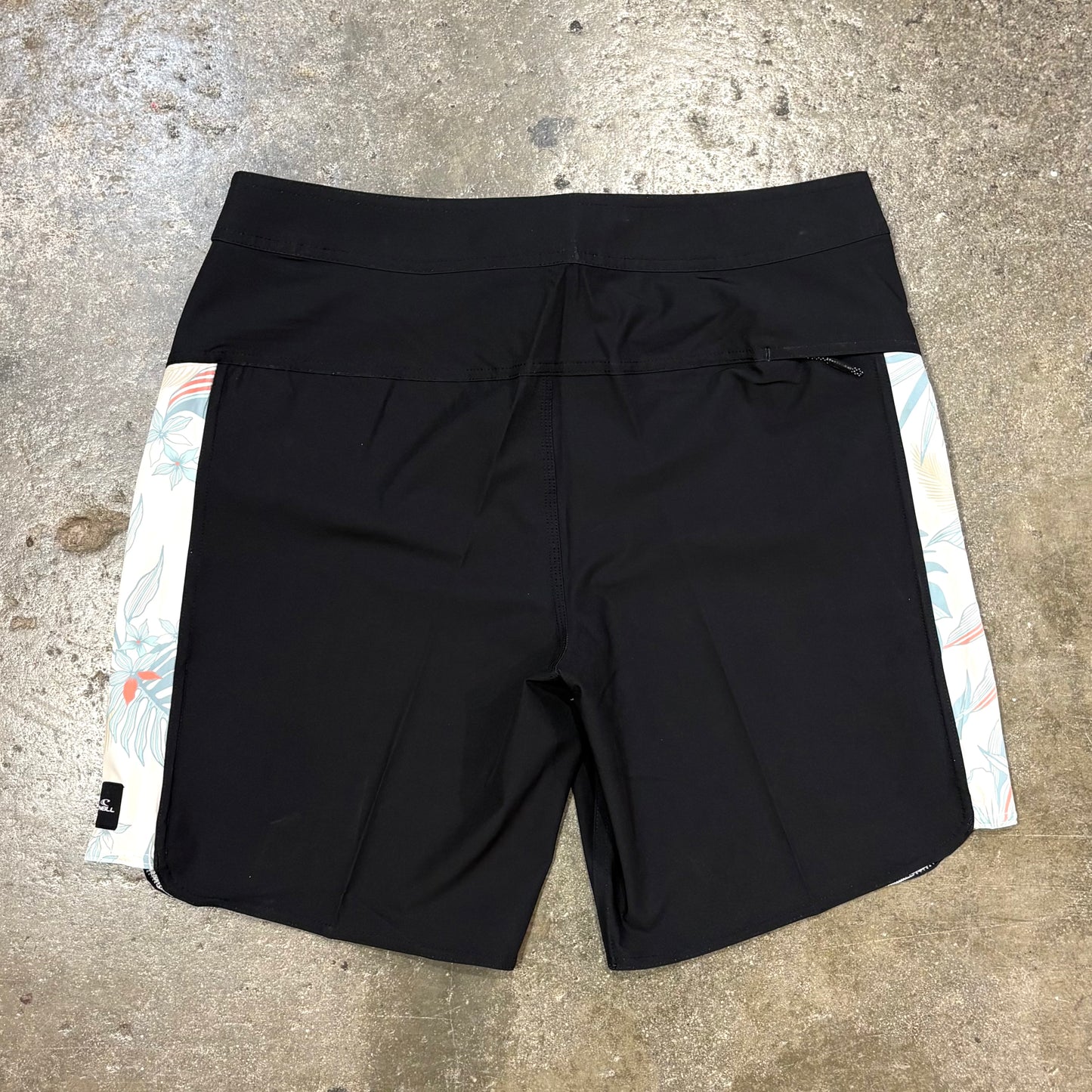 Black shorts with colorful side panels on a concrete surface