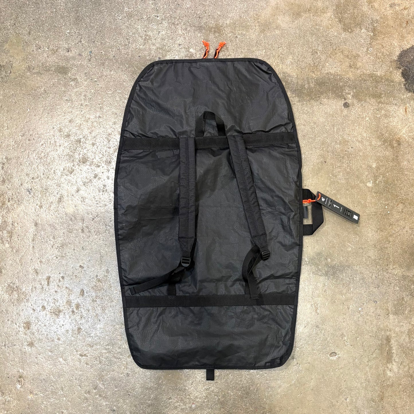 Black bag with orange straps on a concrete surface