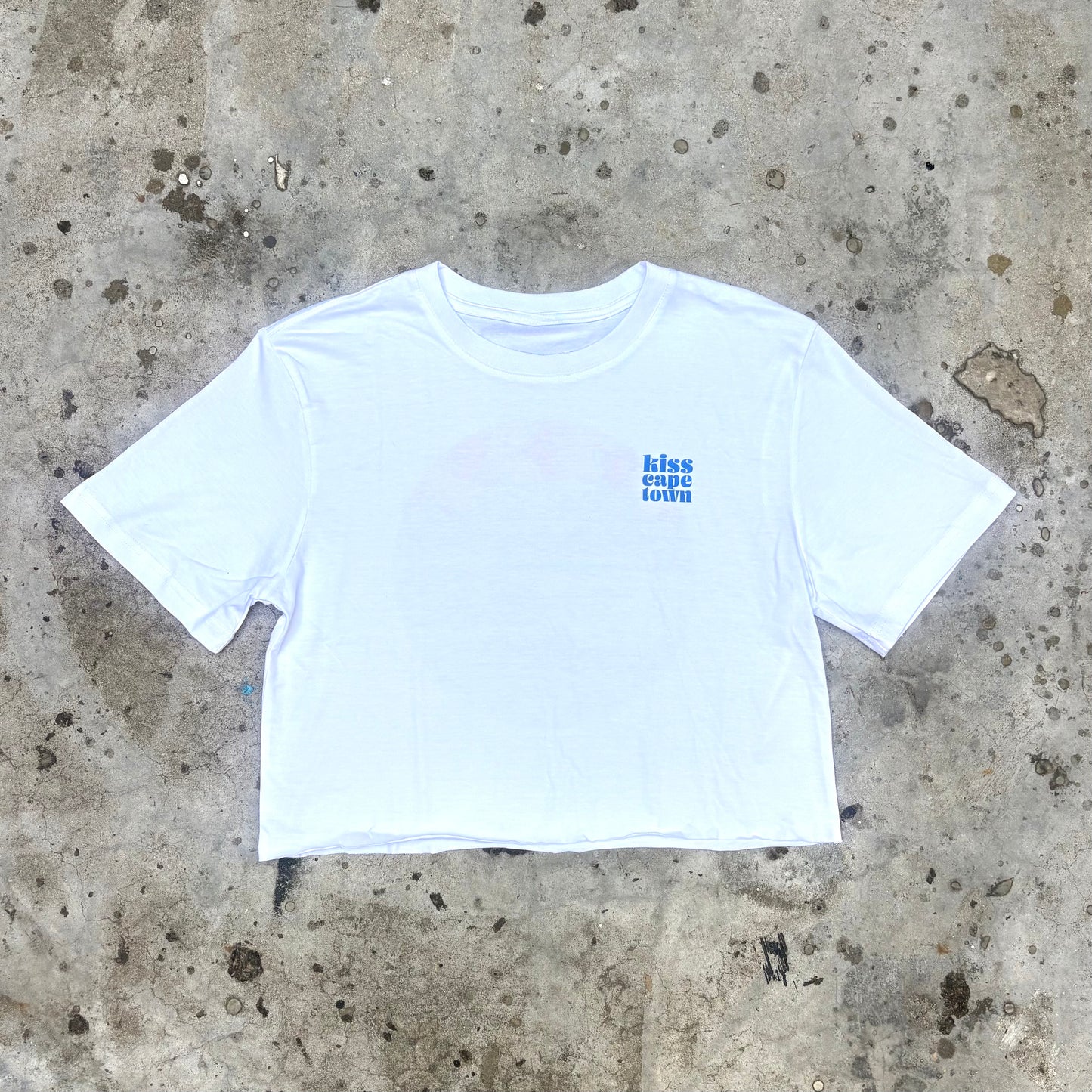 White crop top with blue text on a concrete surface