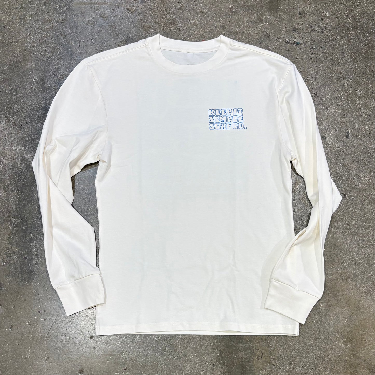 White long-sleeve shirt with blue text on a gray concrete surface