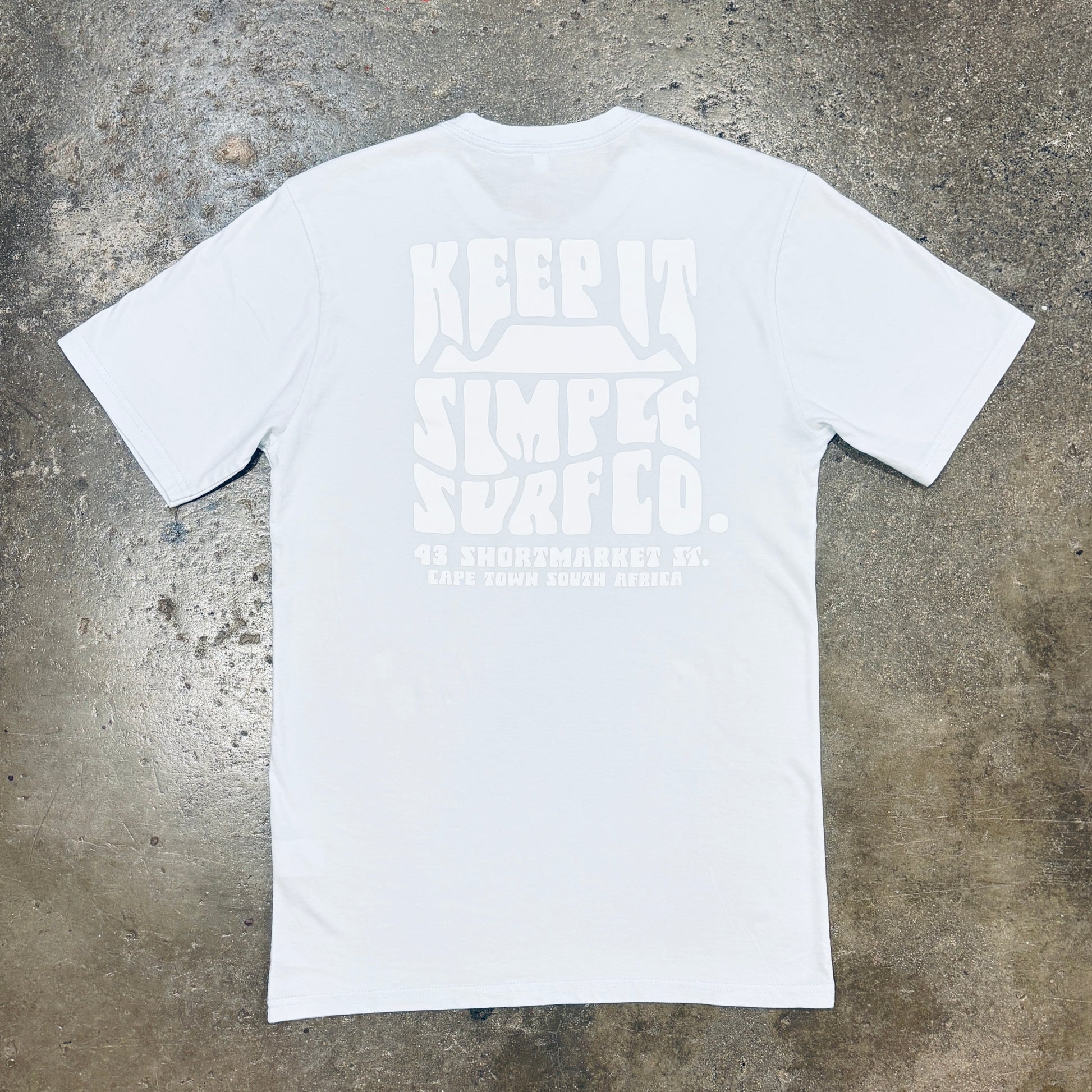 A sky blue short-sleeve t-shirt with a large, tonal white graphic print on the front reading 'KEEP IT SIMPLE SURF CO.'