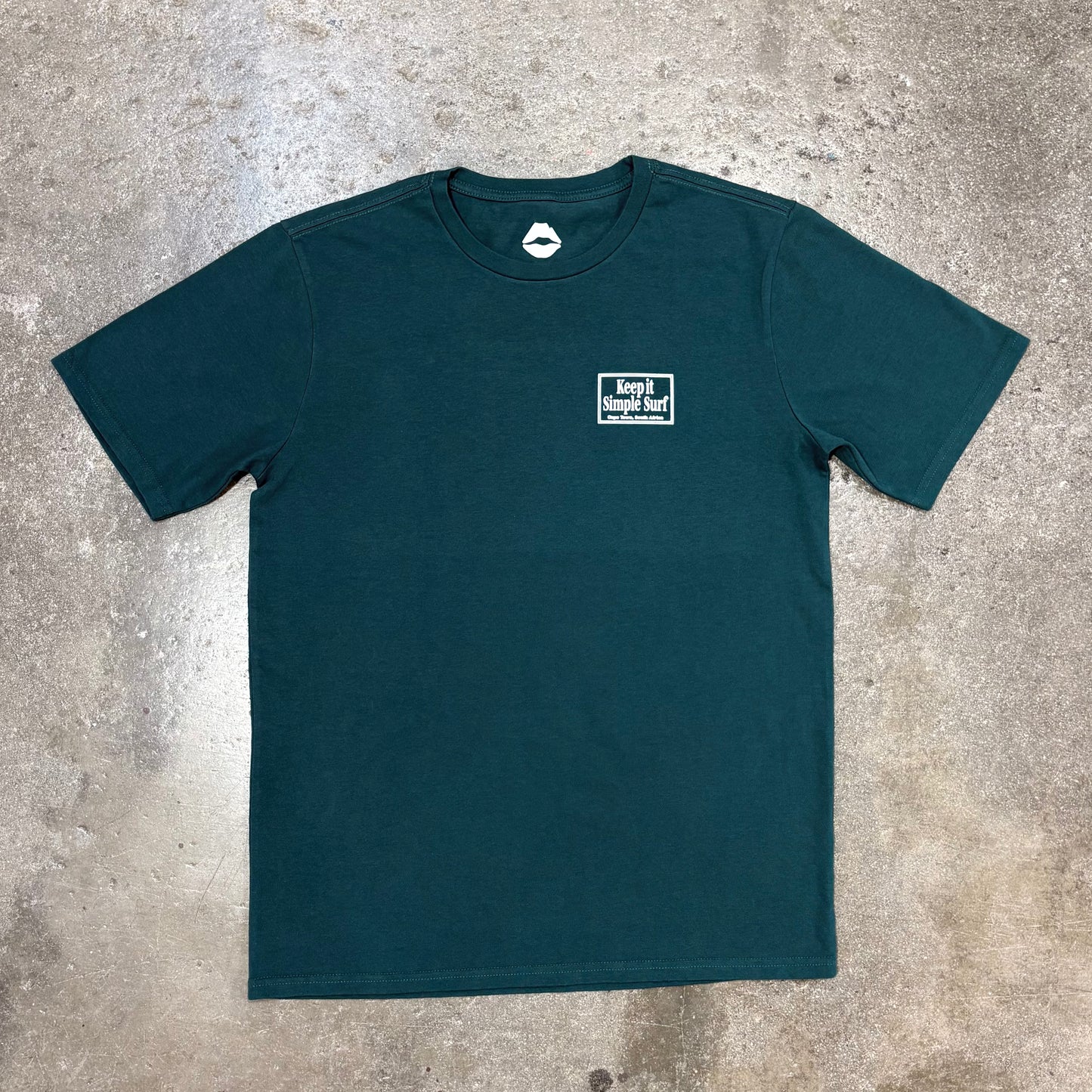 Teal t-shirt with a logo on a concrete surface