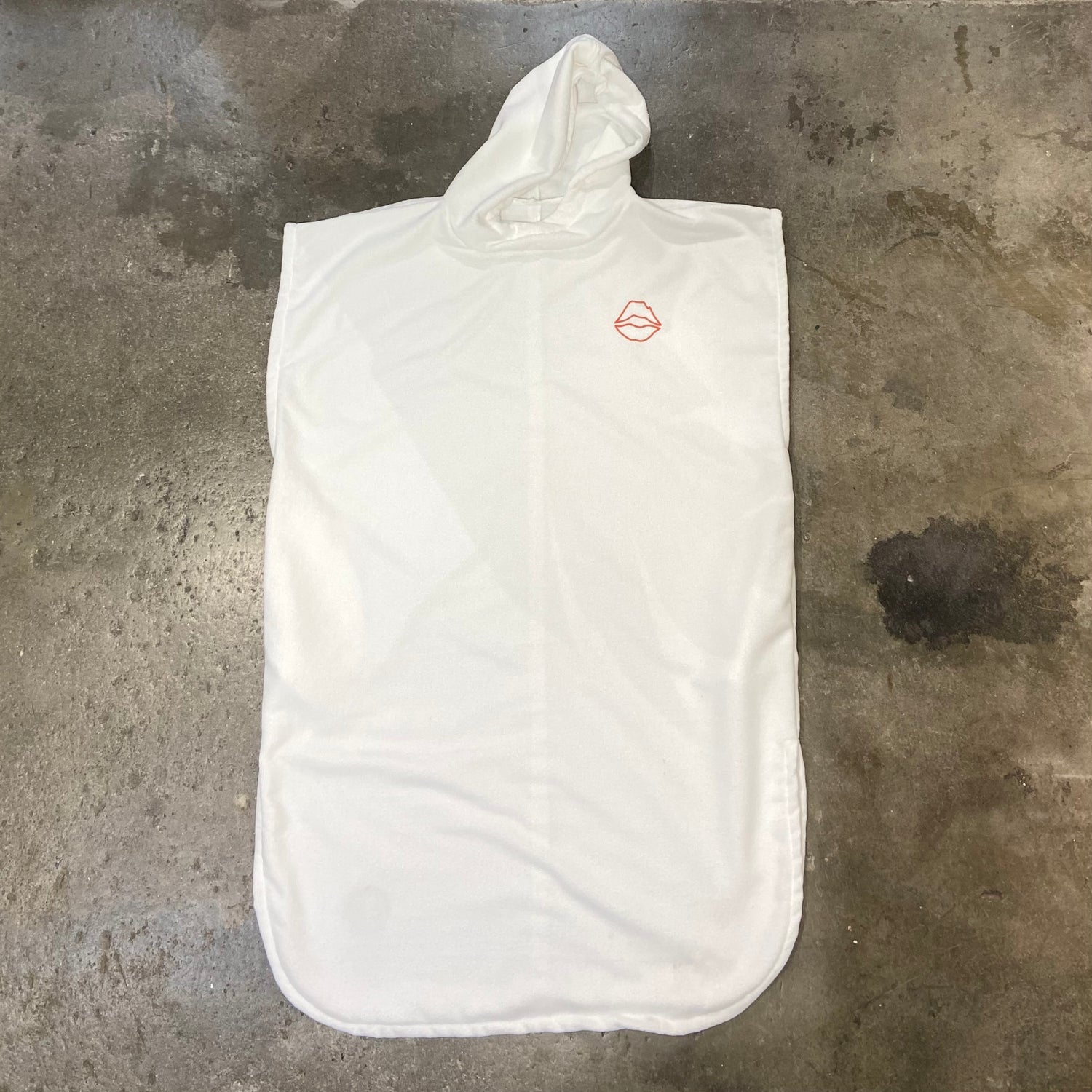 KISS SURF PONCHO WHITE on a concrete surface