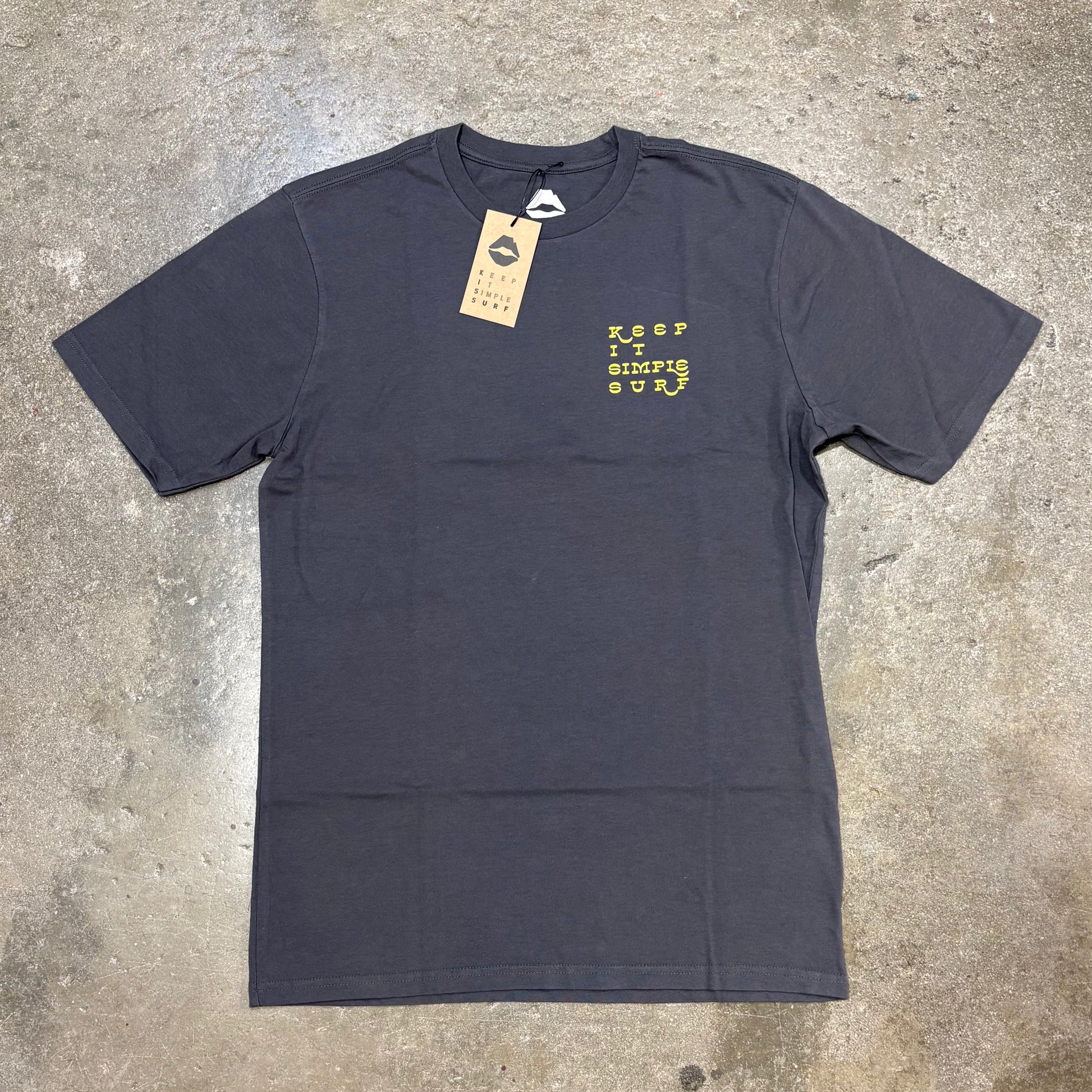 Dark gray Kiss t-shirt with yellow text on a concrete surface