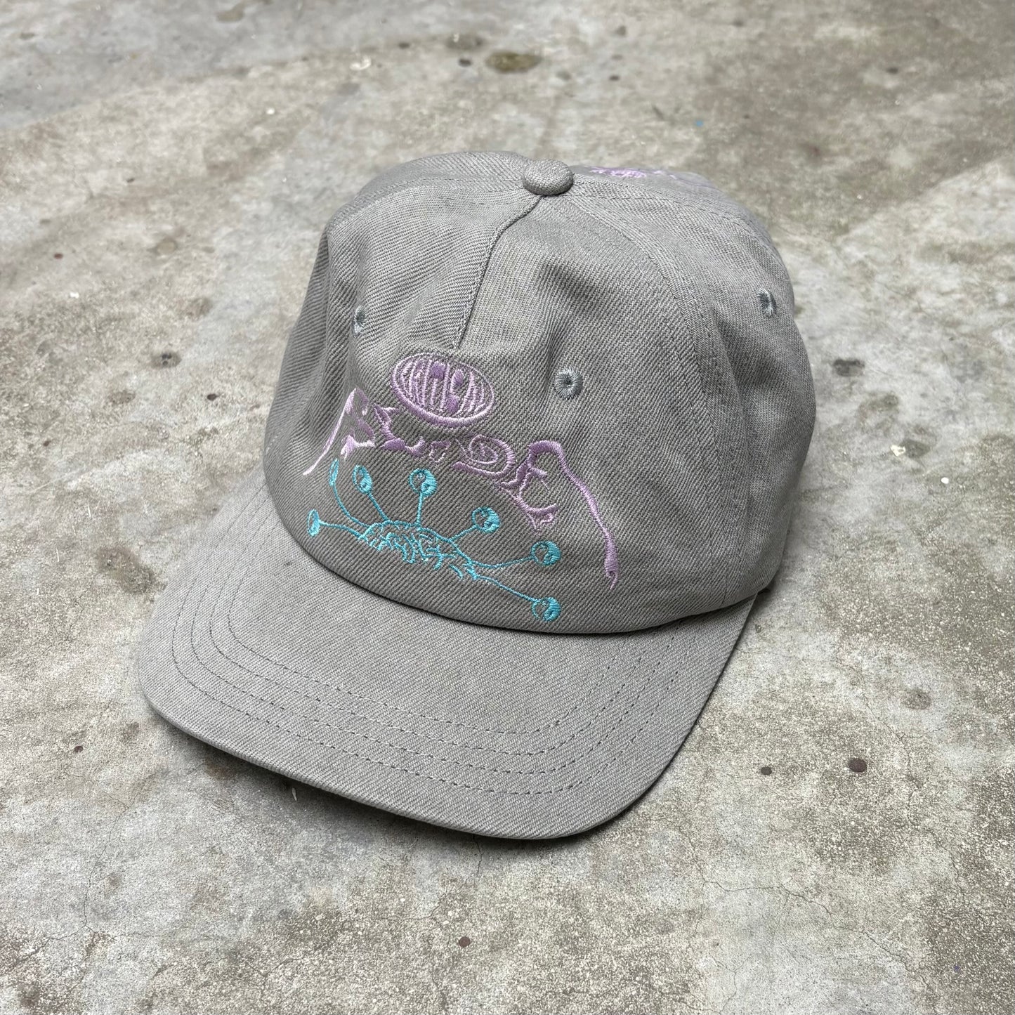 Gray cap with embroidered design on a concrete surface
