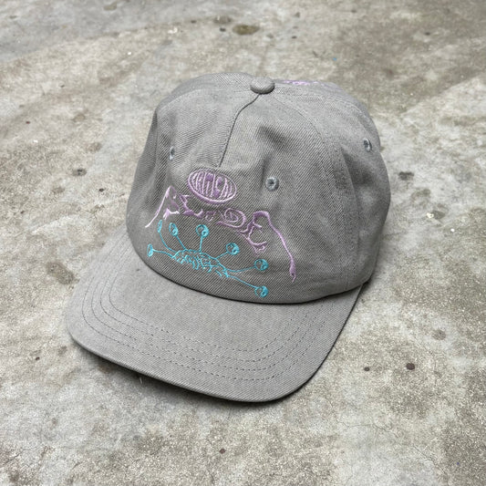 Gray cap with embroidered design on a concrete surface