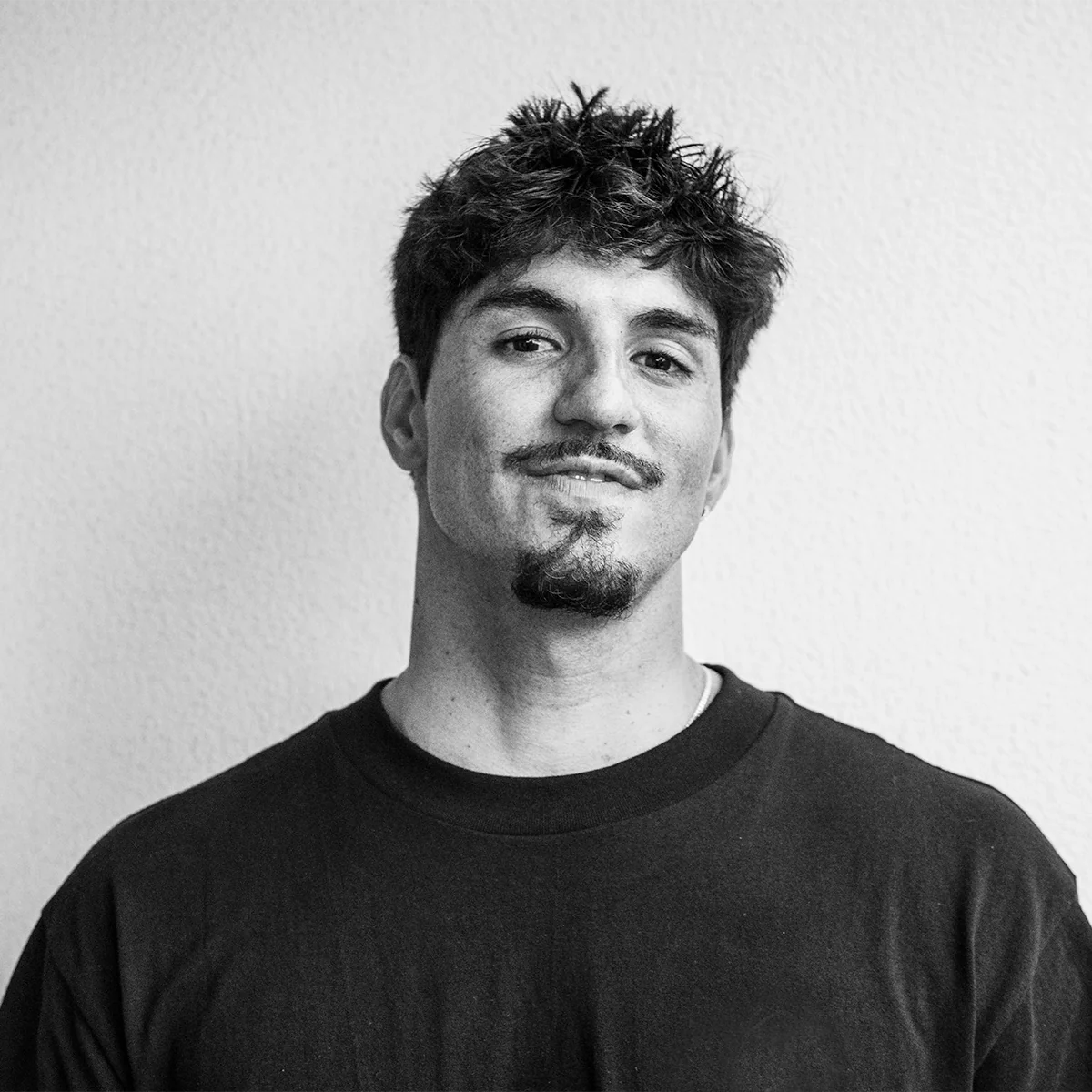 Black and white portrait of Gabriel Medina wearing a dark shirt against a plain background