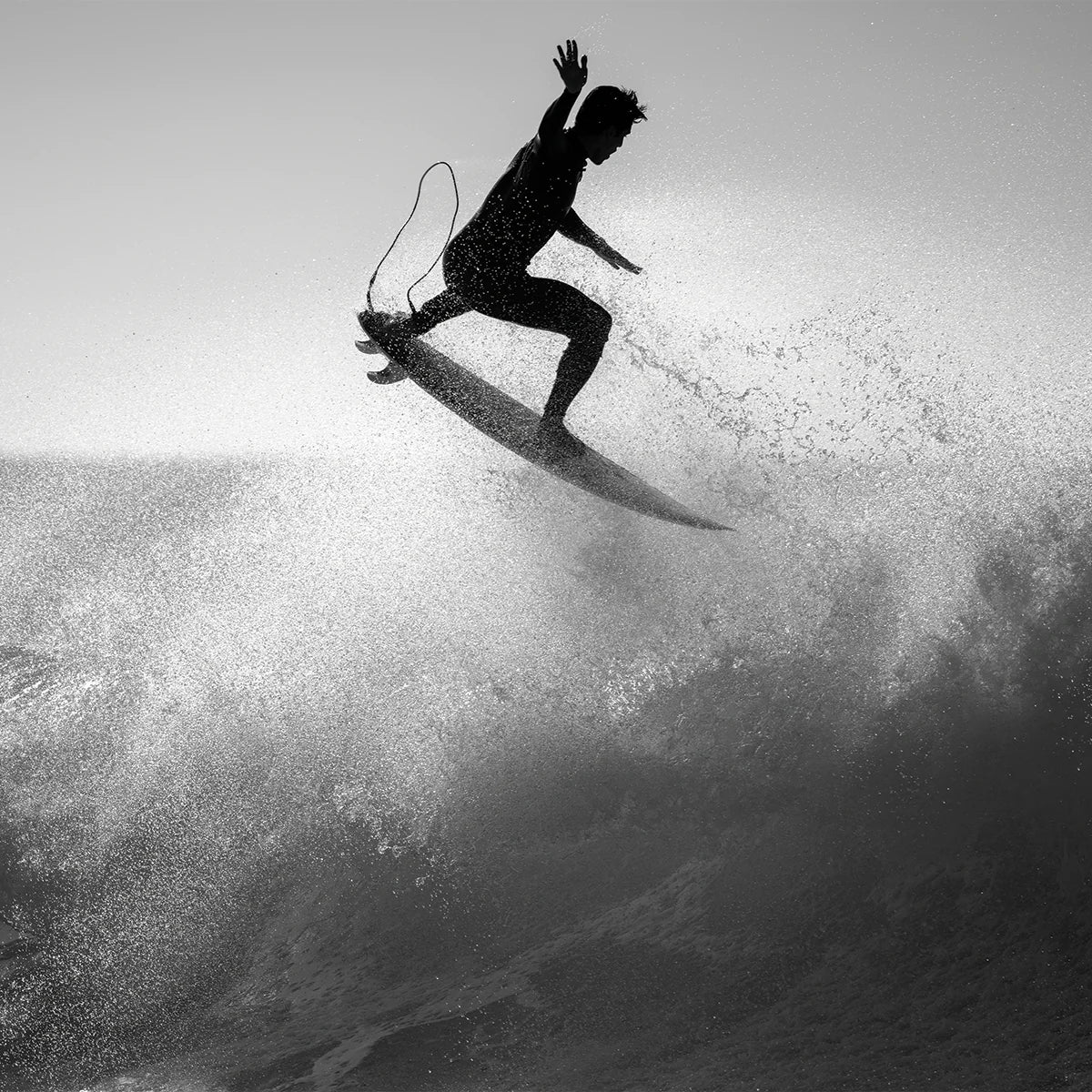 Black and white silhouette of a surfer riding a wave