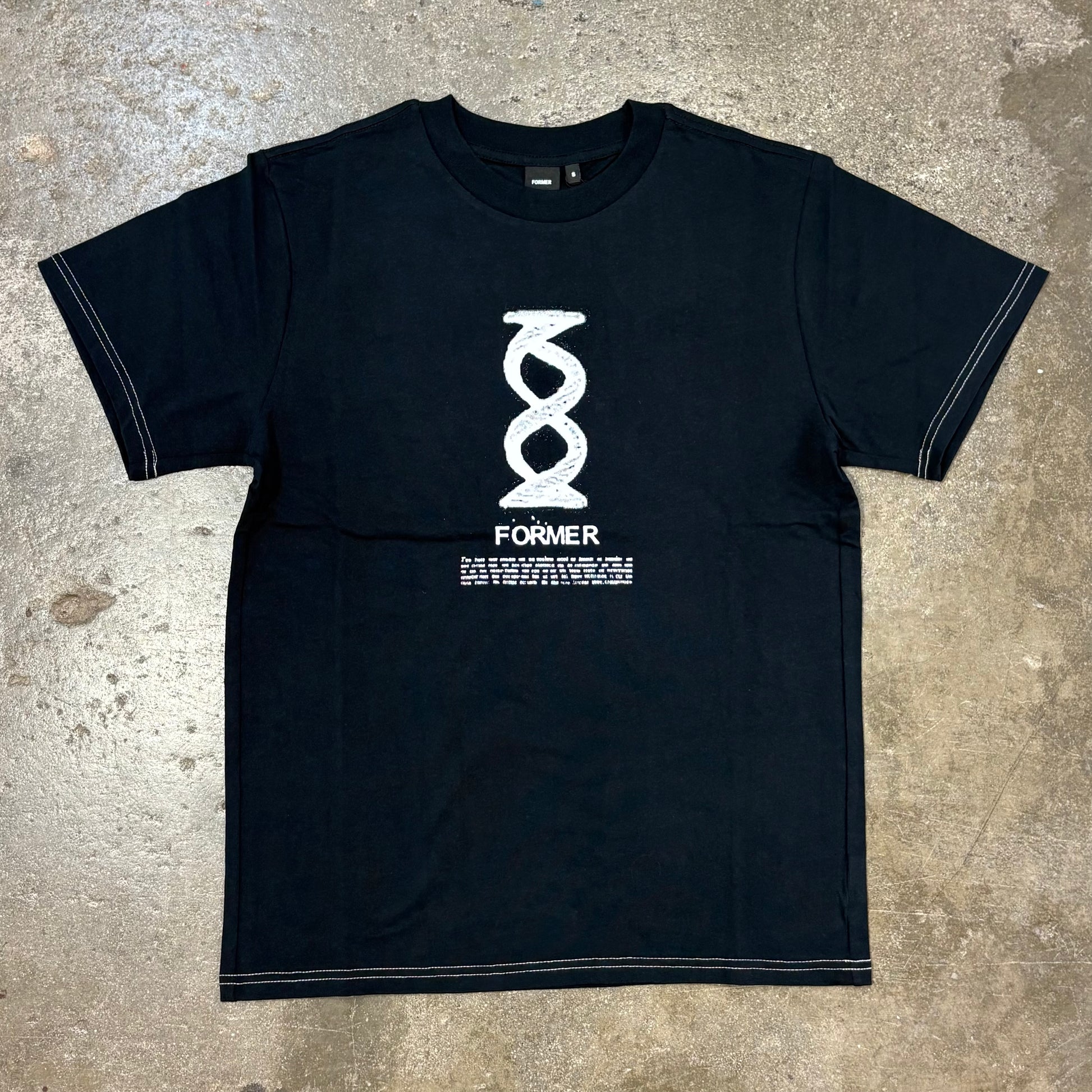 Black t-shirt with white graphic design on a concrete surface