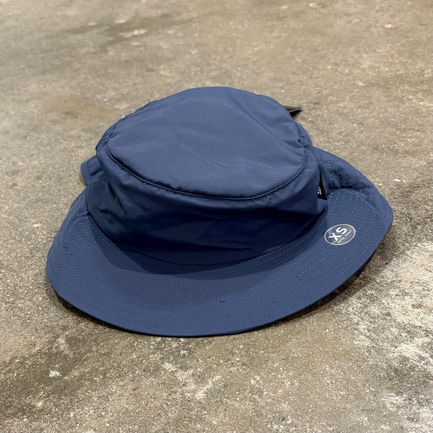 A blueOcean & Earth surf hat with a stiff peak on a concrete floor