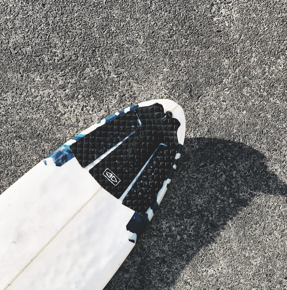 White surfboard with black Pin Tail Traction and Ocean&EARTH LOGO on a textured gray STREET surface