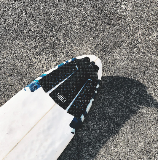 White surfboard with black Pin Tail Traction and Ocean&EARTH LOGO on a textured gray STREET surface