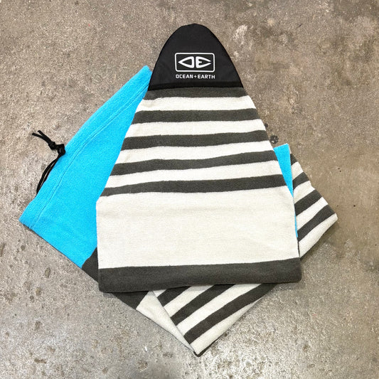 Striped towel and blue pouch on a concrete surface with 'Ocean Earth' branding.