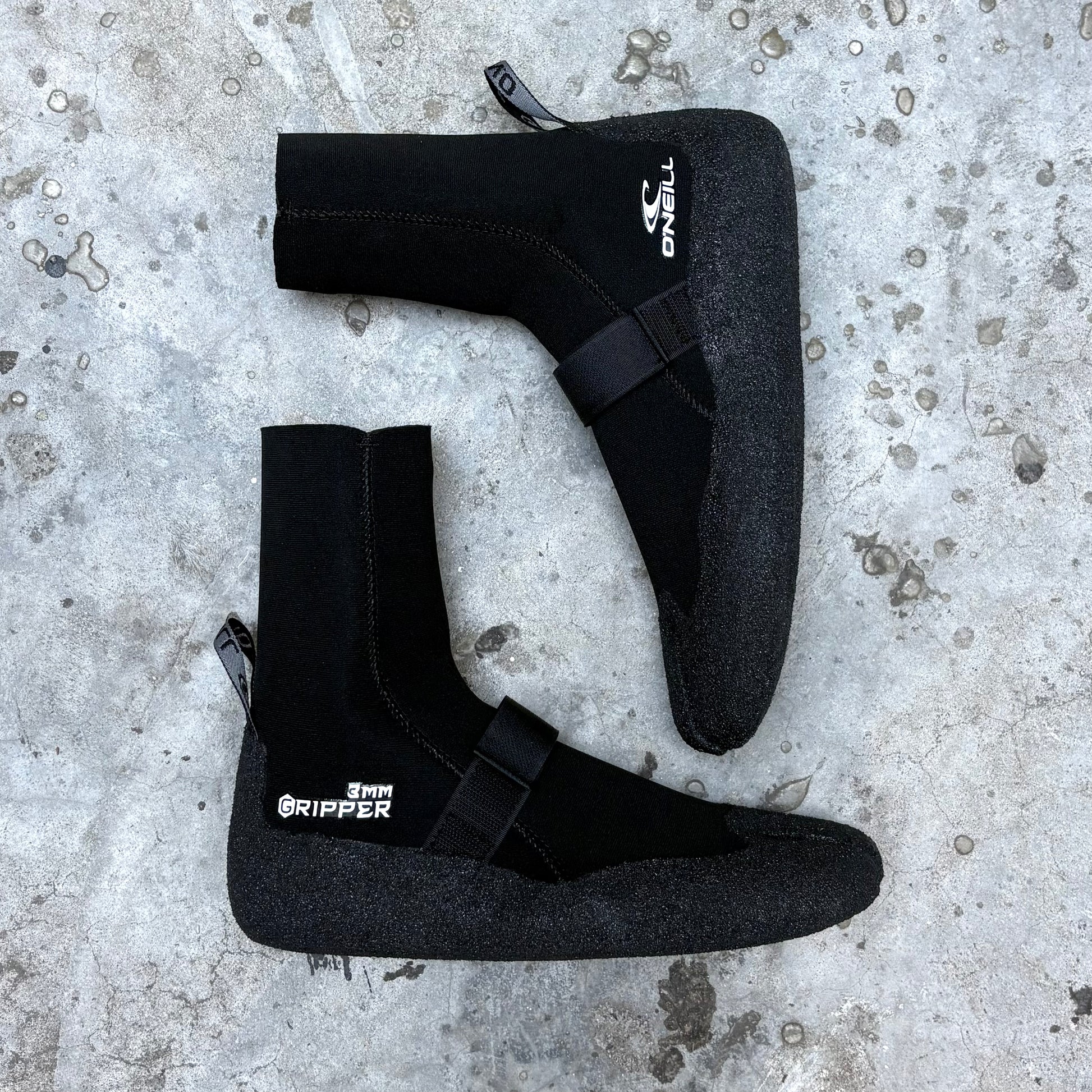 Black wetsuit boots with 'O'Neill' branding on a concrete surface