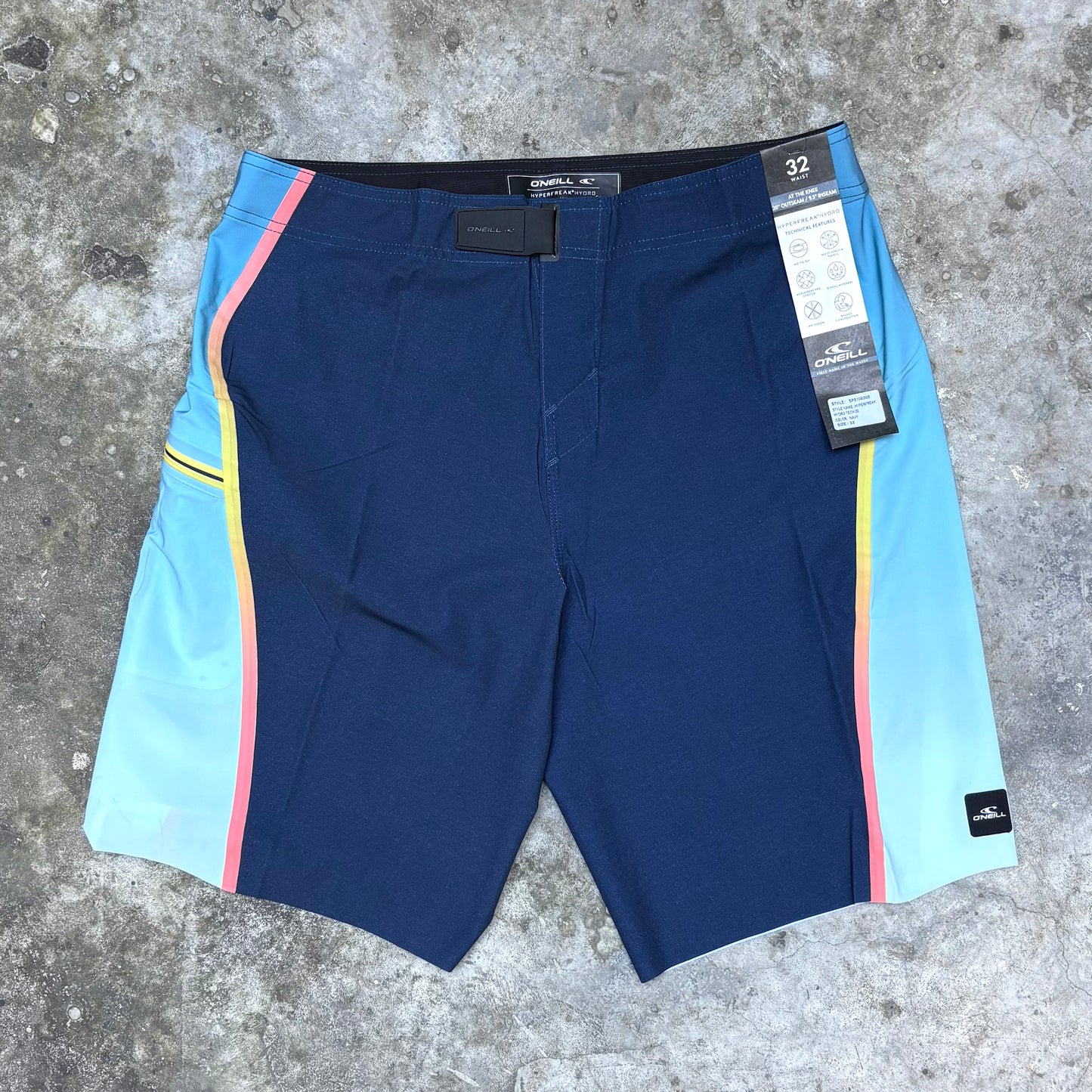 Blue shorts with colorful side panels on a concrete surface