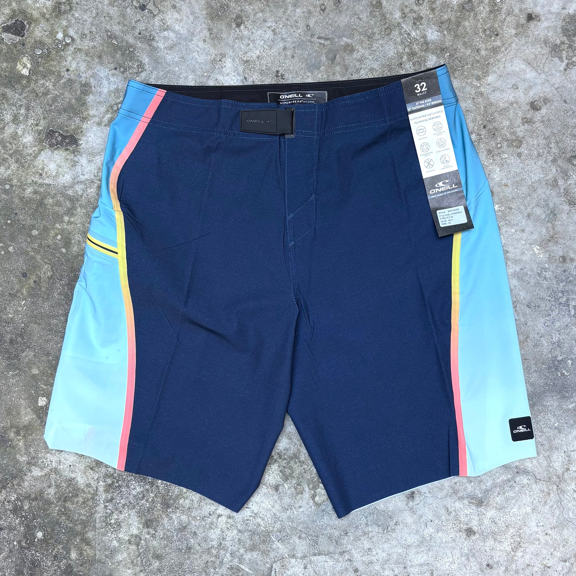 Blue shorts with colorful side panels on a concrete surface