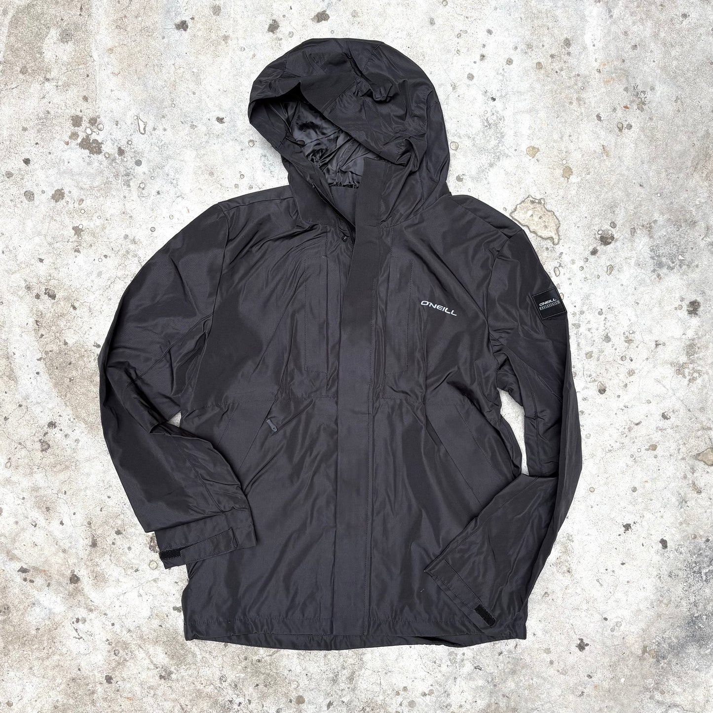 Black jacket with a hood on a textured concrete surface
