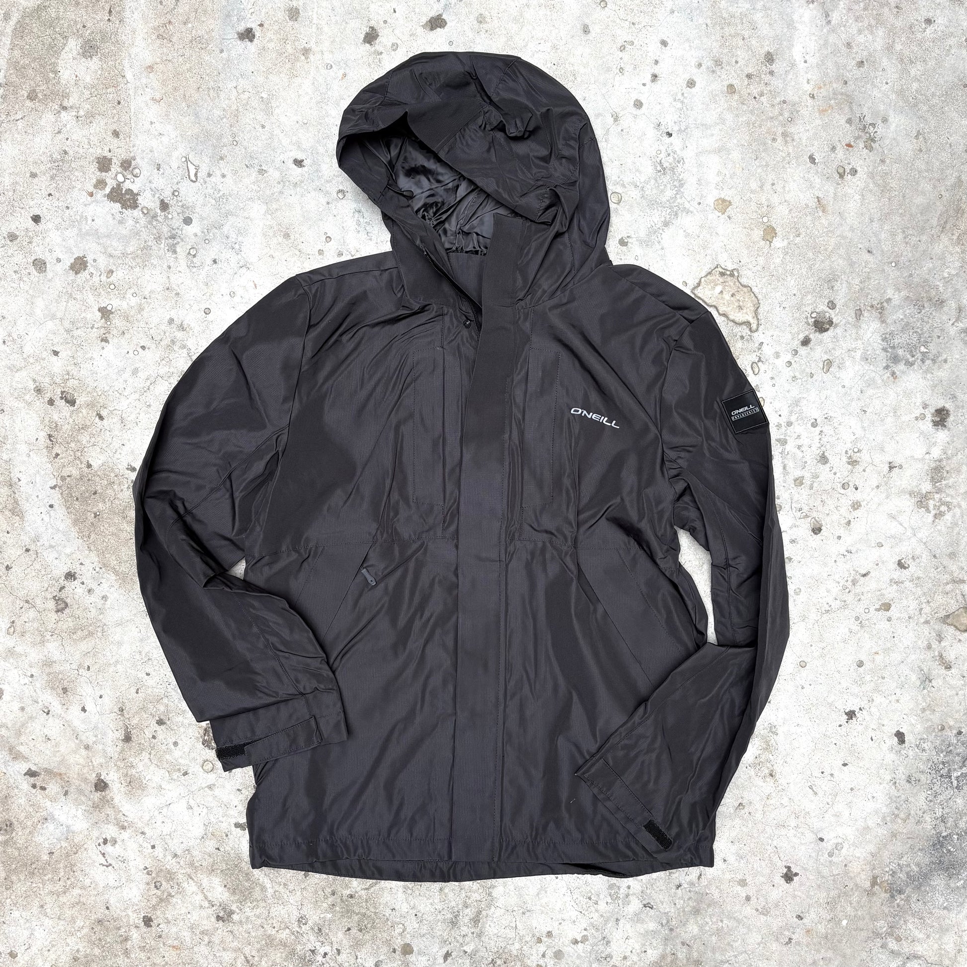 Black jacket with a hood on a textured concrete surface
