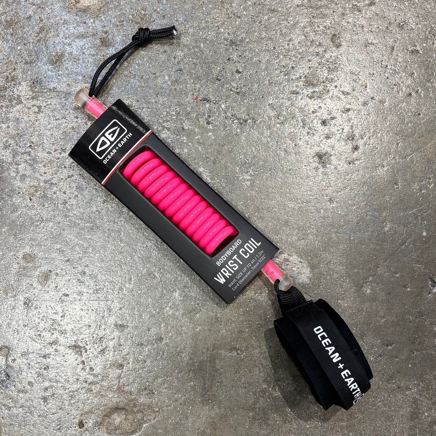 Pink wrist coil with black handle on a concrete surface