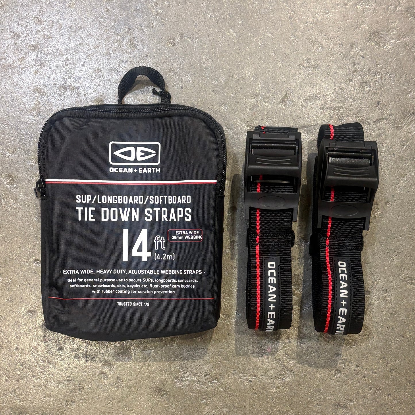 Black tie down straps with packaging labeled 'Ocean + Earth' on a concrete surface.