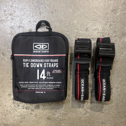 Black tie down straps with packaging labeled 'Ocean + Earth' on a concrete surface.