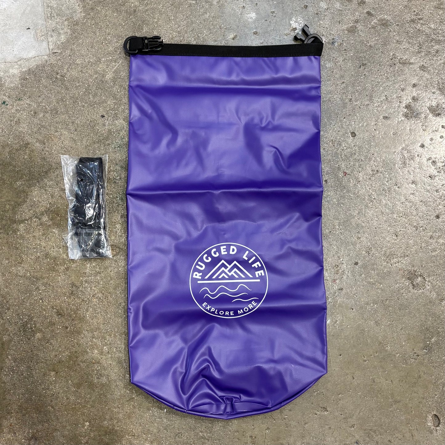 Purple dry bag with 'Rugged Life' logo on a concrete surface
