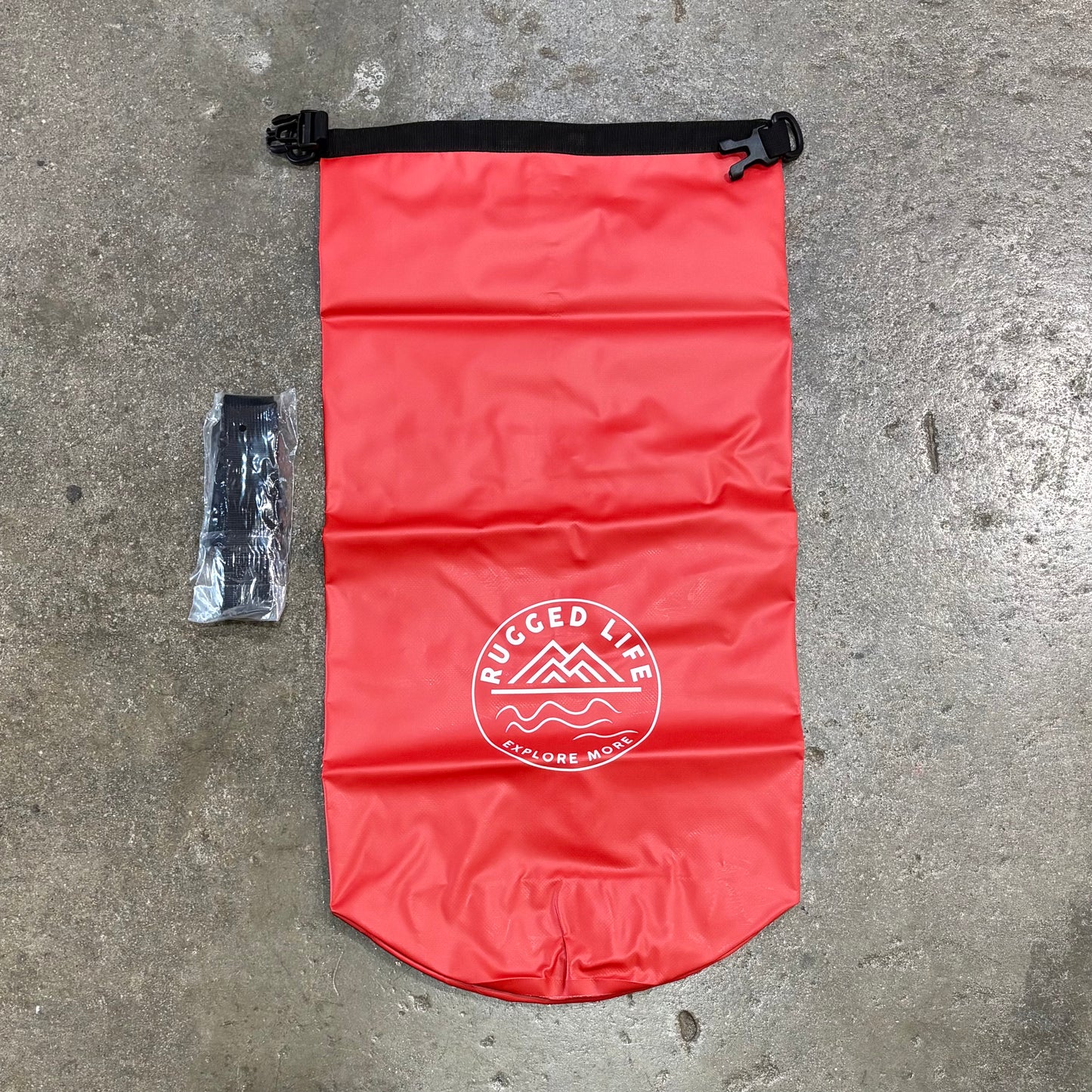 Red dry bag with 'Rugged Life' logo on a concrete surface