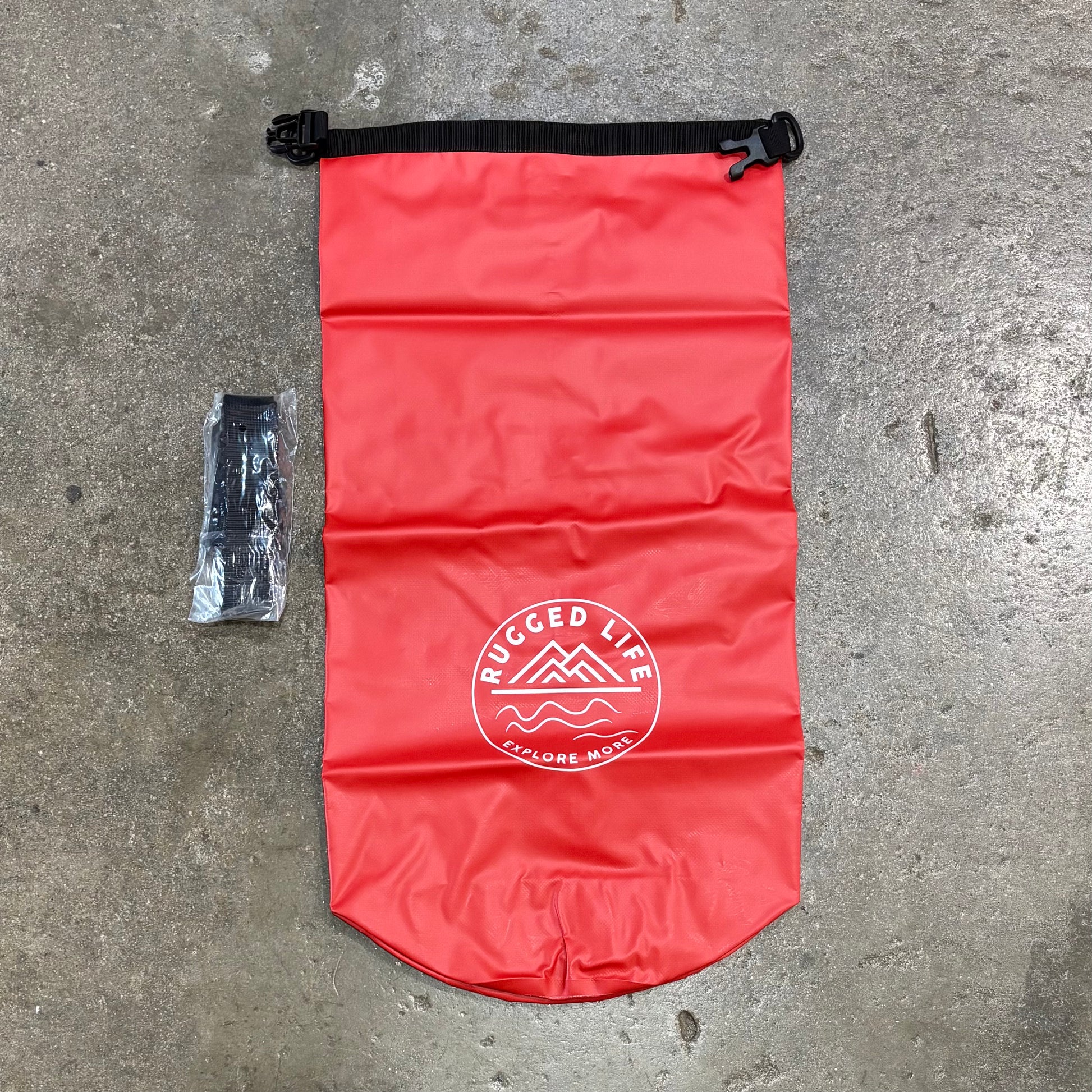 Red dry bag with 'Rugged Life' logo on a concrete surface