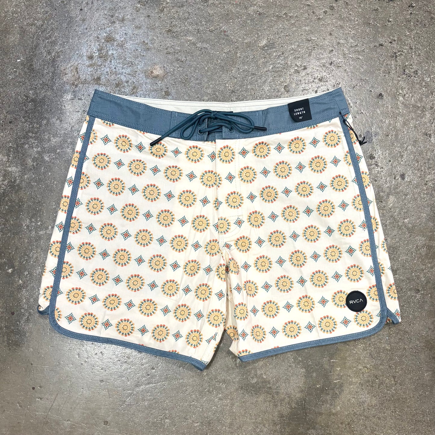 Patterned shorts with blue trim on a gray concrete surface