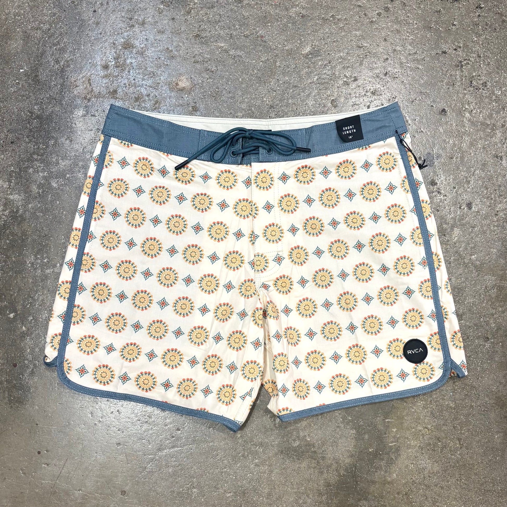 Patterned shorts with blue trim on a gray concrete surface