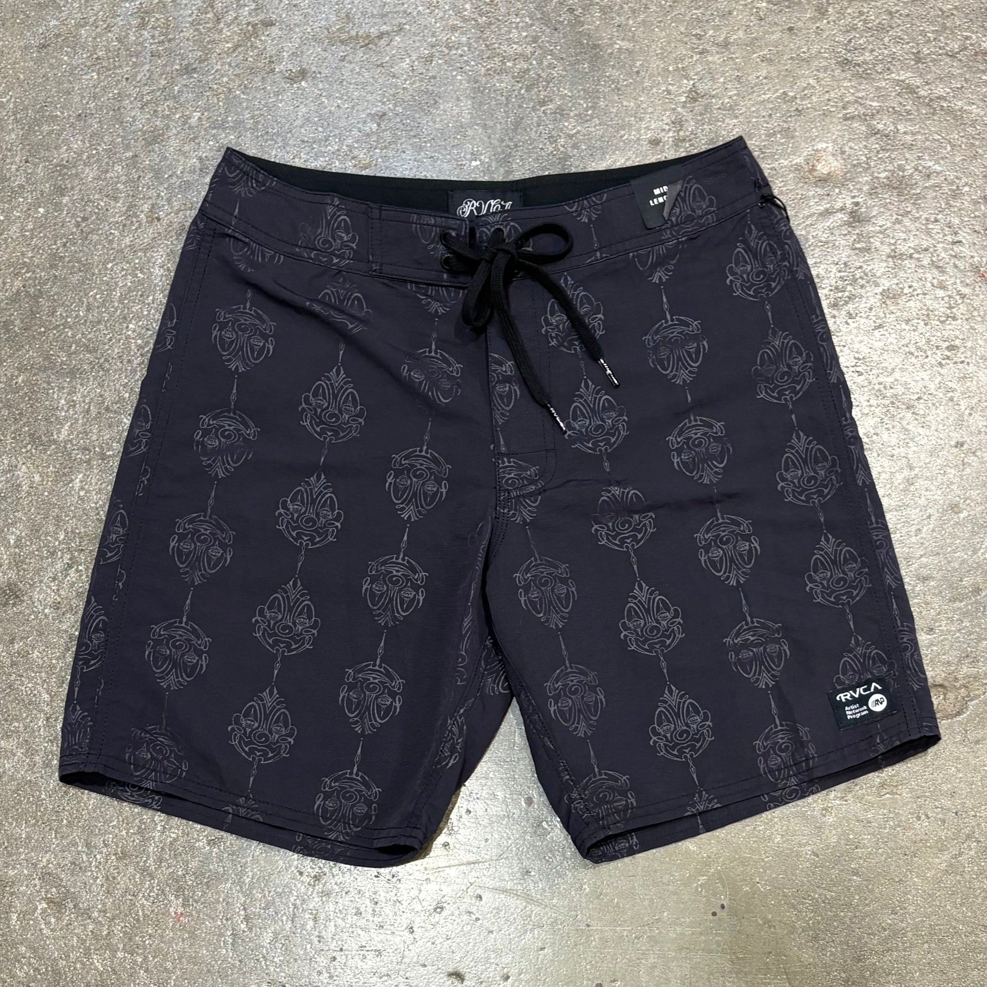 Black shorts with a pattern on a gray concrete surface