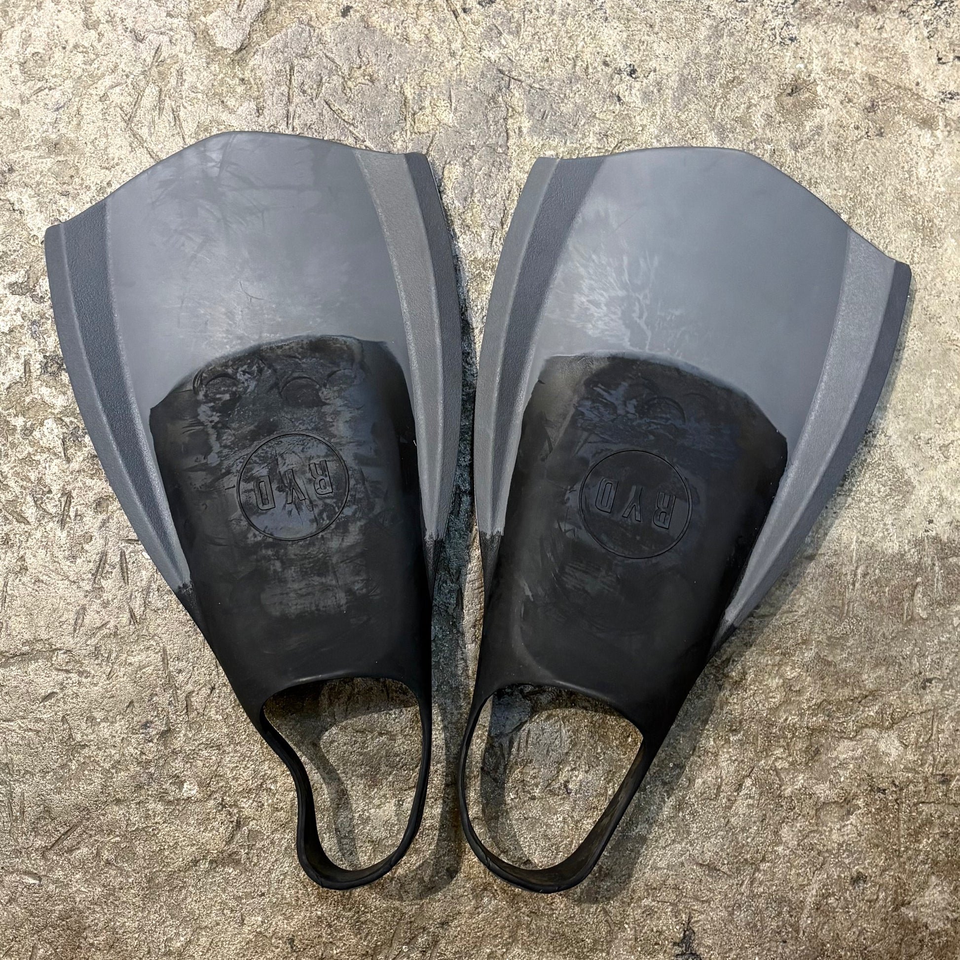 Pair of gray and black diving fins on a textured surface