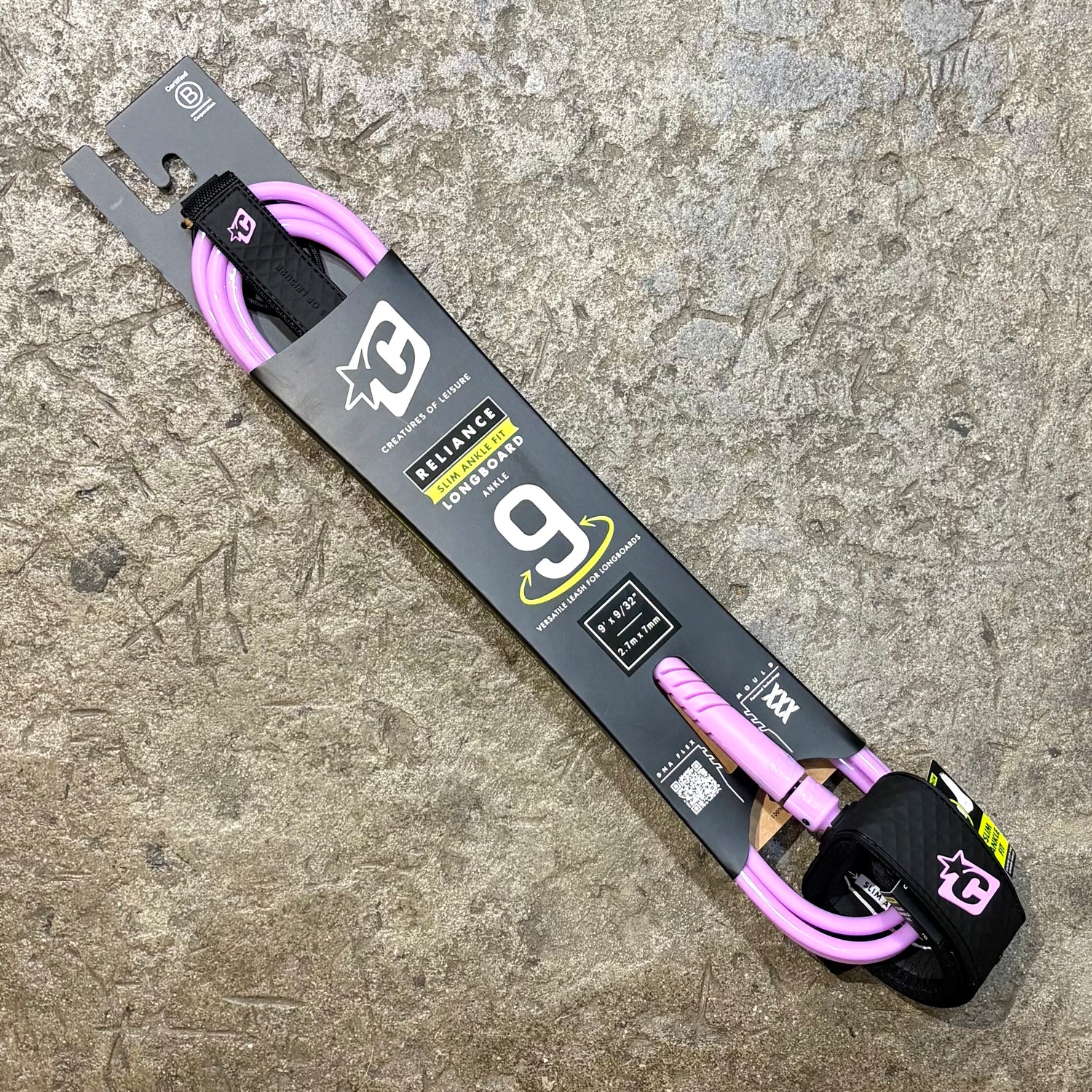 Pink and black 9' longboard  leash with packaging on a textured surface