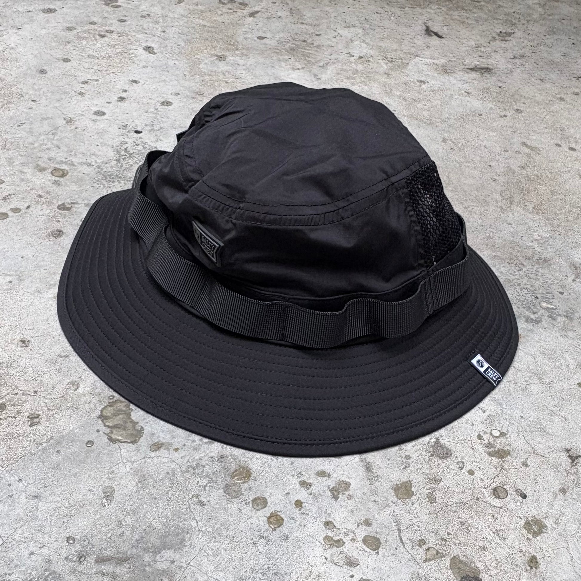Black bucket hat on a textured concrete surface